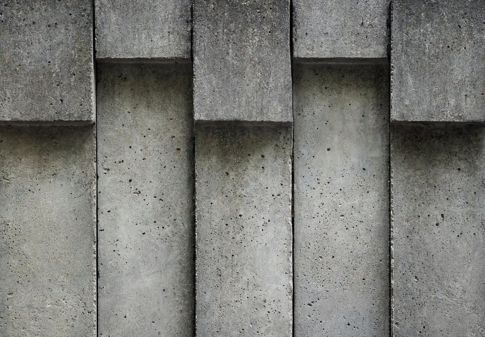 Gray concrete wall with vertical rectangular panels and shadowed recesses