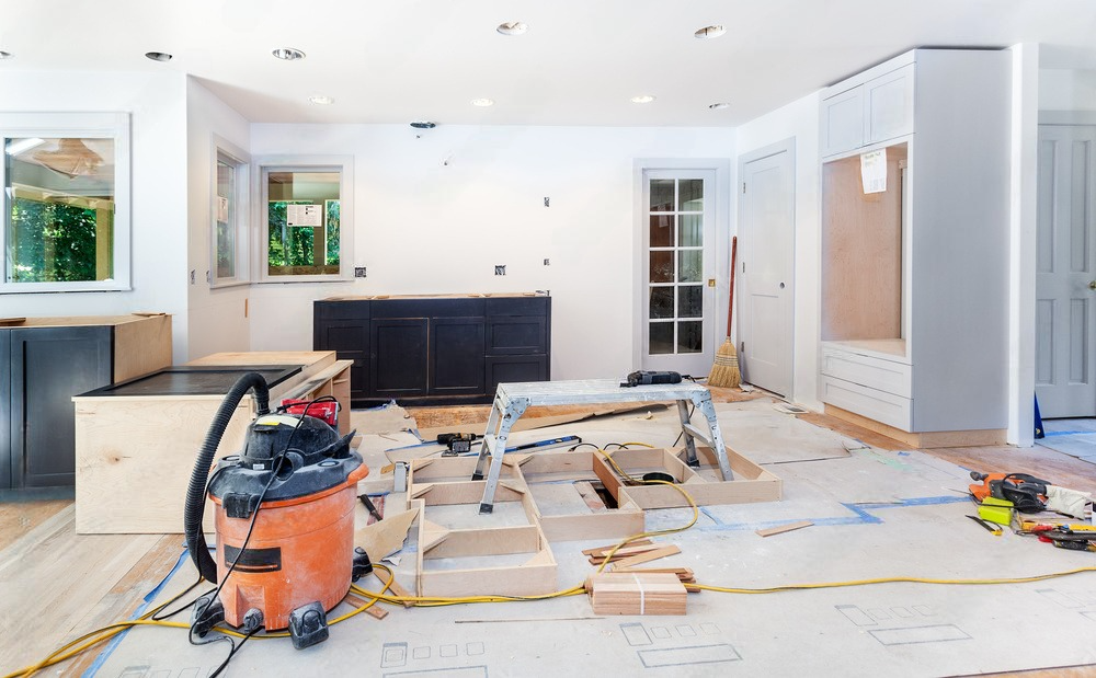 A vacuum cleaner is sitting on the floor of a living room under construction.