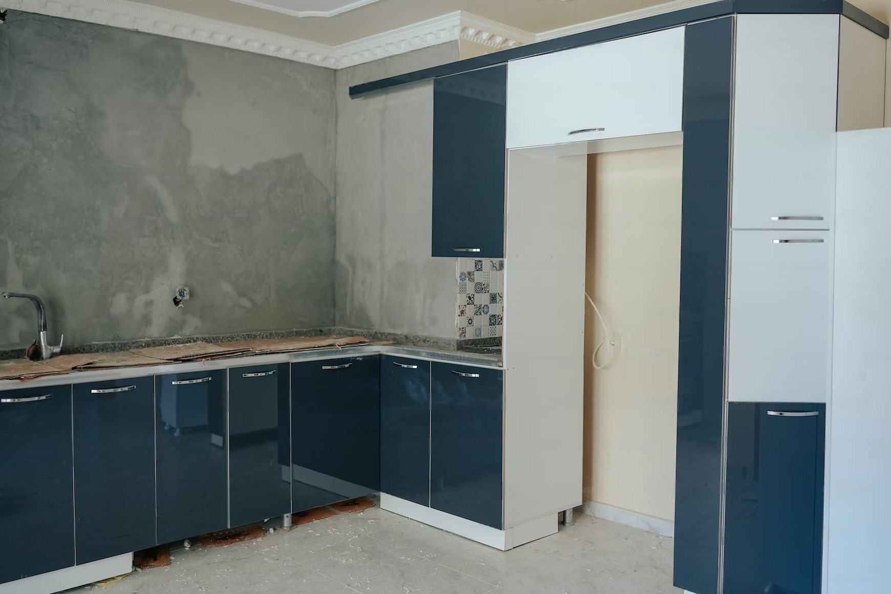 A kitchen with blue and white cabinets and a white refrigerator.