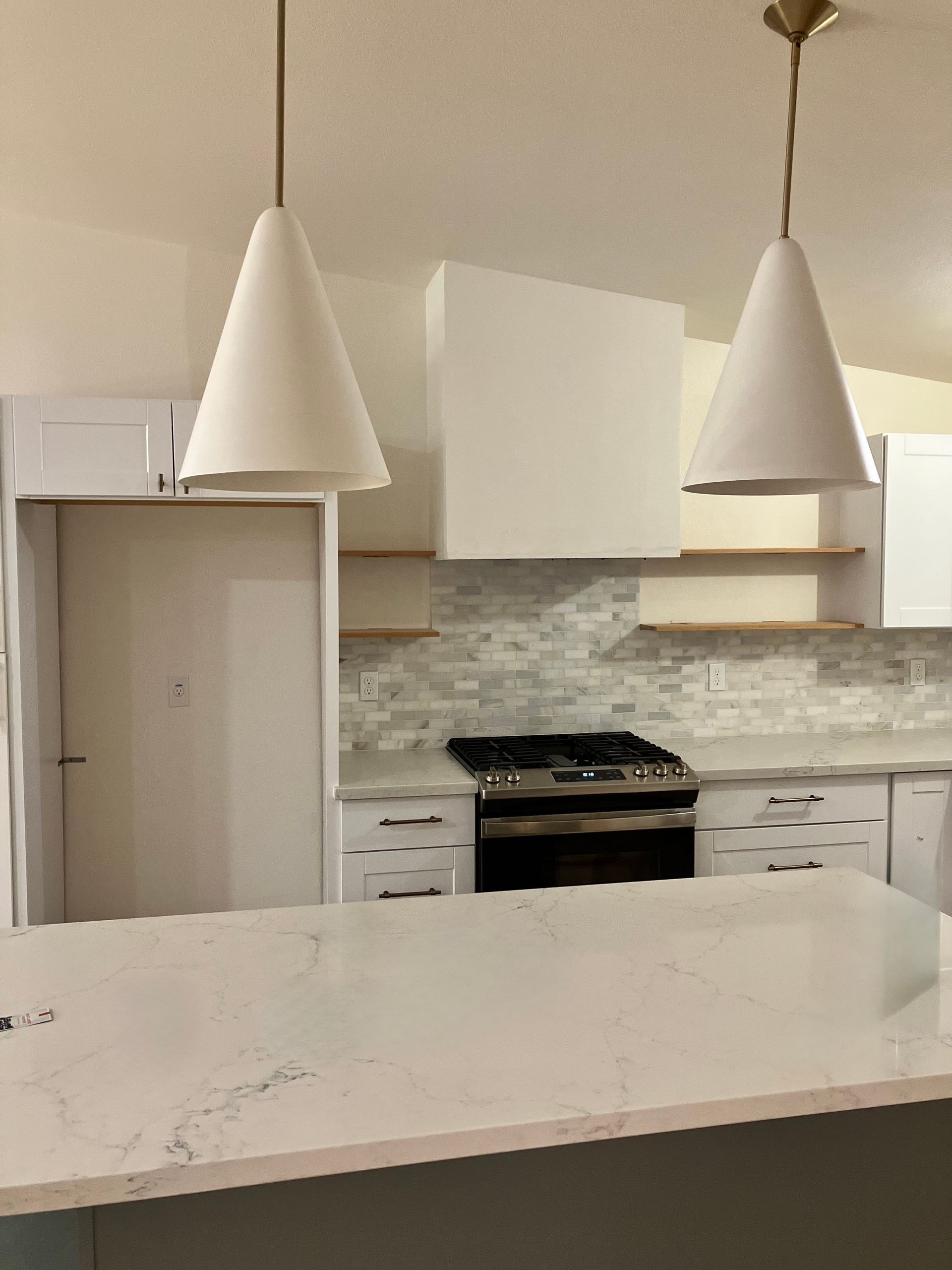 Kitchen with white cabinets, light fixtures, and a marble countertop.