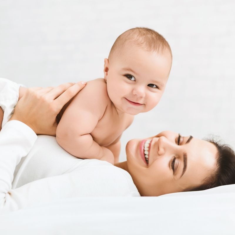Une femme est allongée sur un lit tenant un bébé.