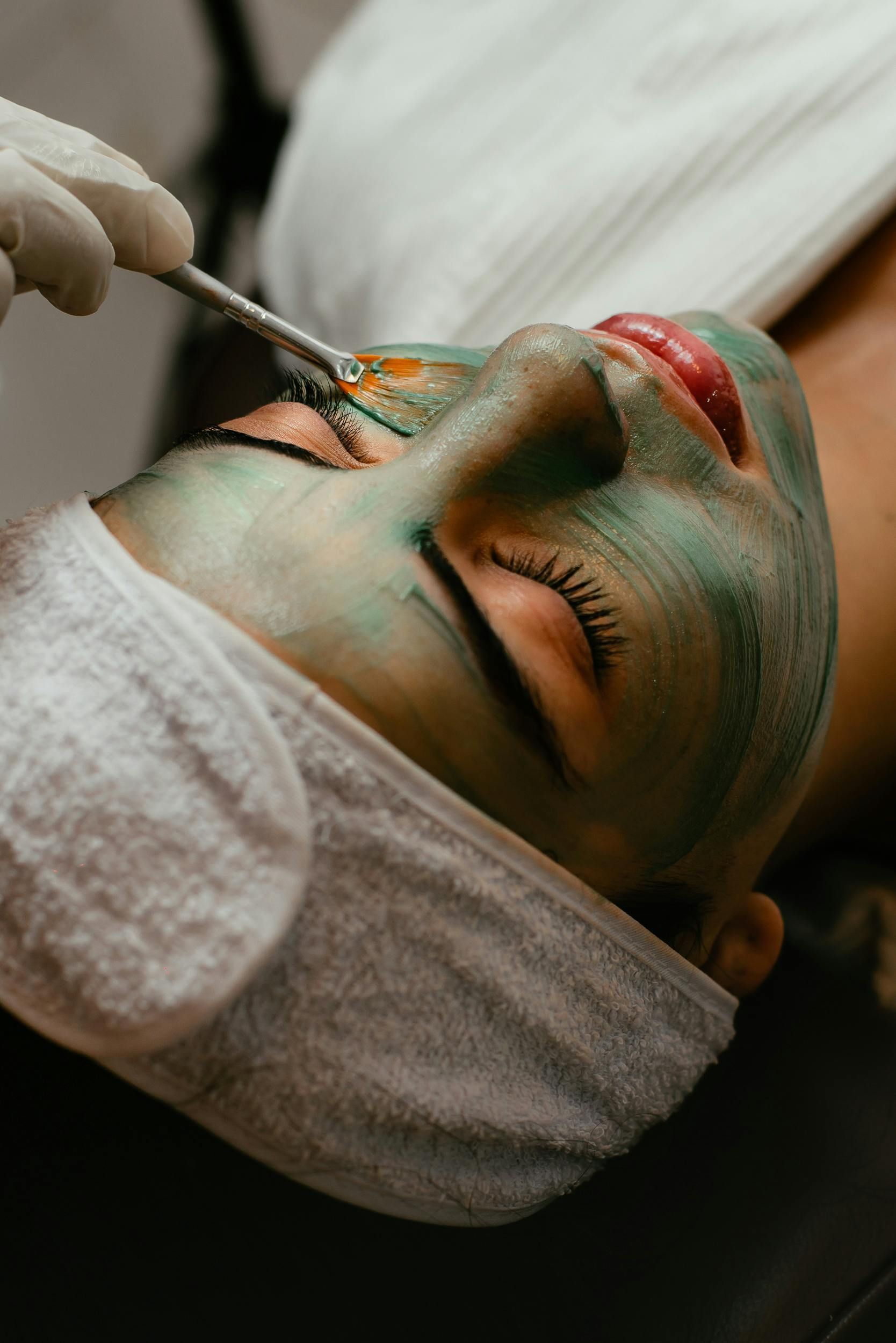Une femme reçoit un masque vert sur son visage.