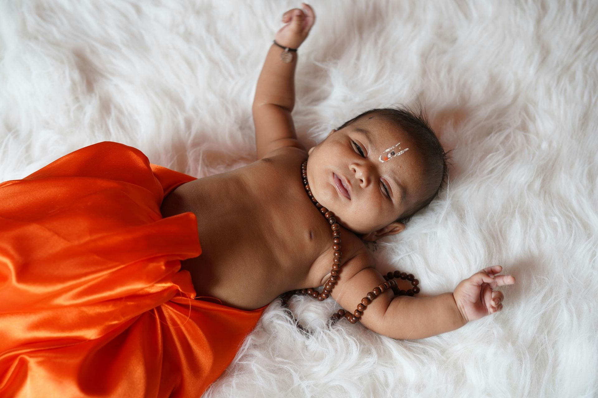 un bébé est positionné sur le dis, avec un drap orange et un collier. 
Yoga bébé à Colmar, Horbourg wihr, ribeauvillé, wintzenheim 