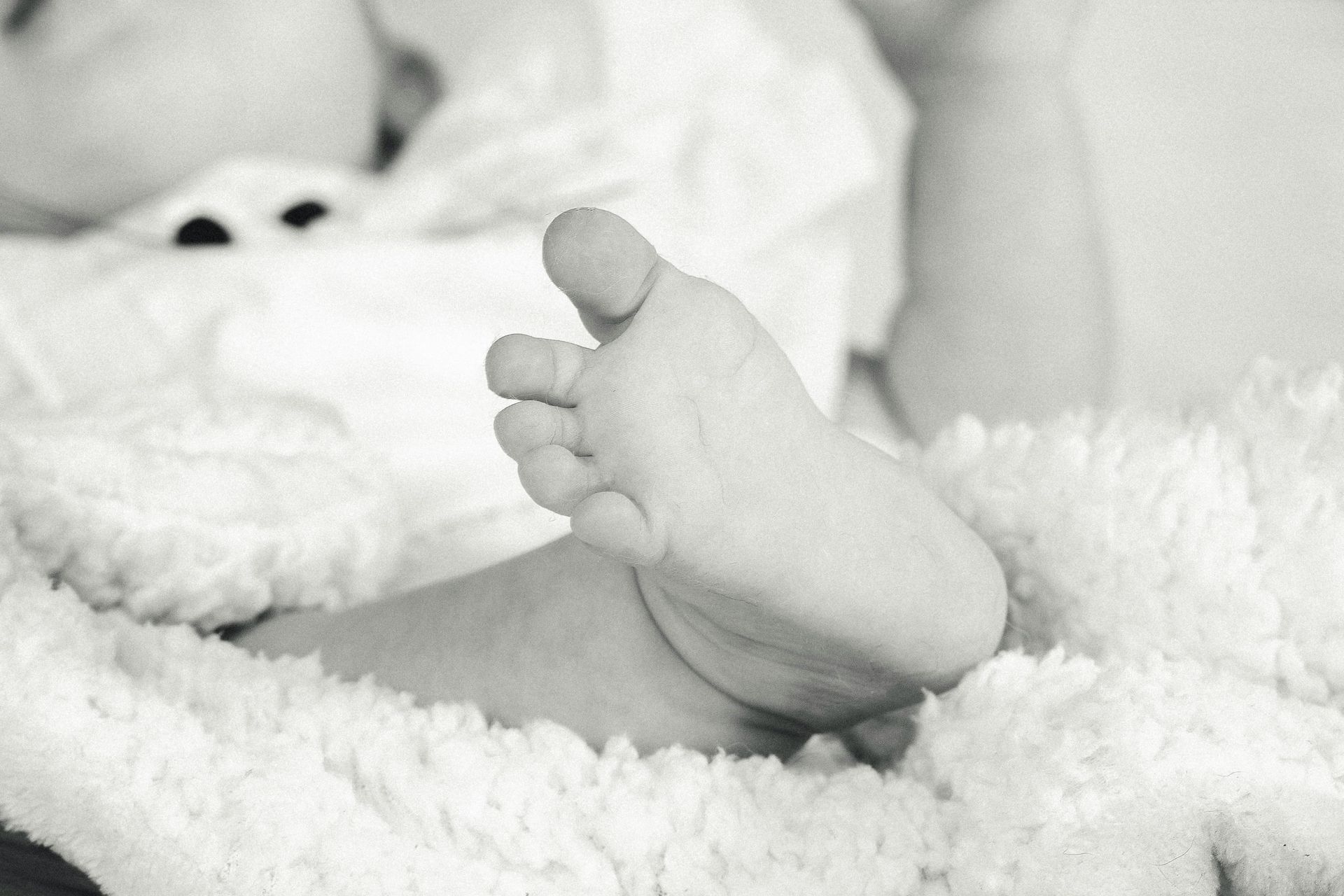 Le pied d'un bébé est posé sur une couverture blanche.