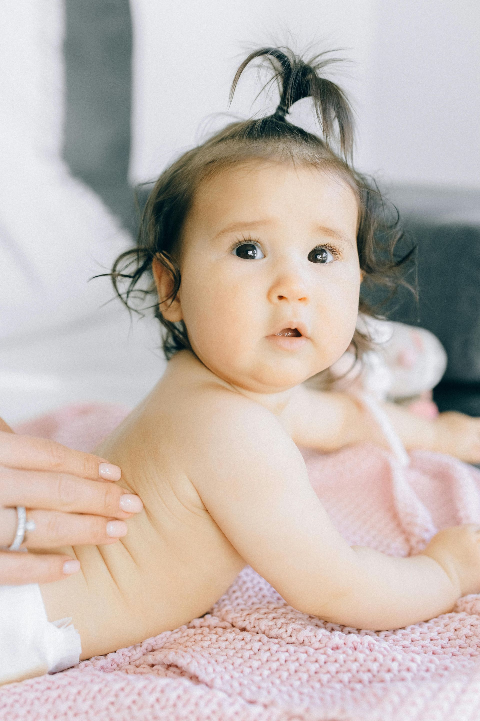 Un bébé est allongé sur une serviette rose et se fait masser