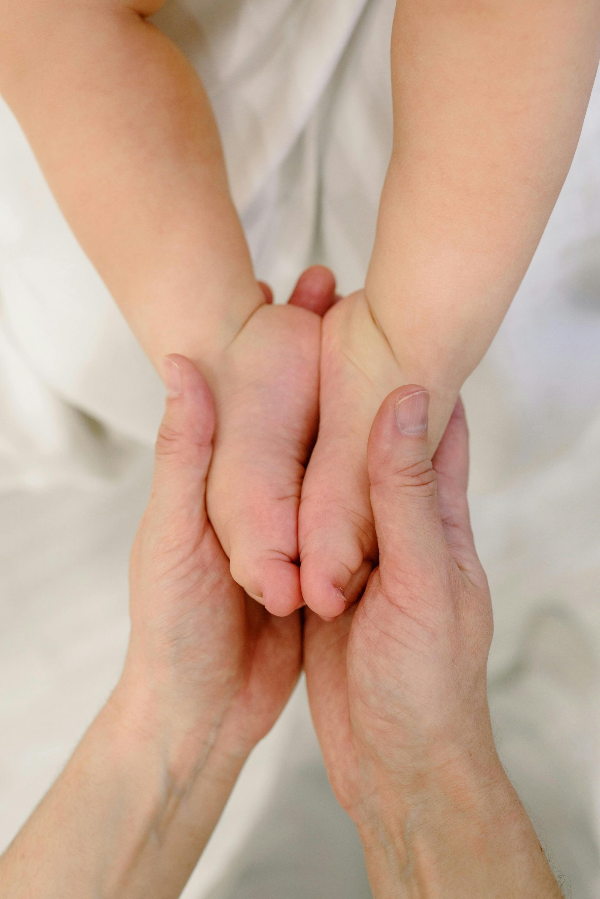 Une personne tient le pied d'un bébé dans ses mains.