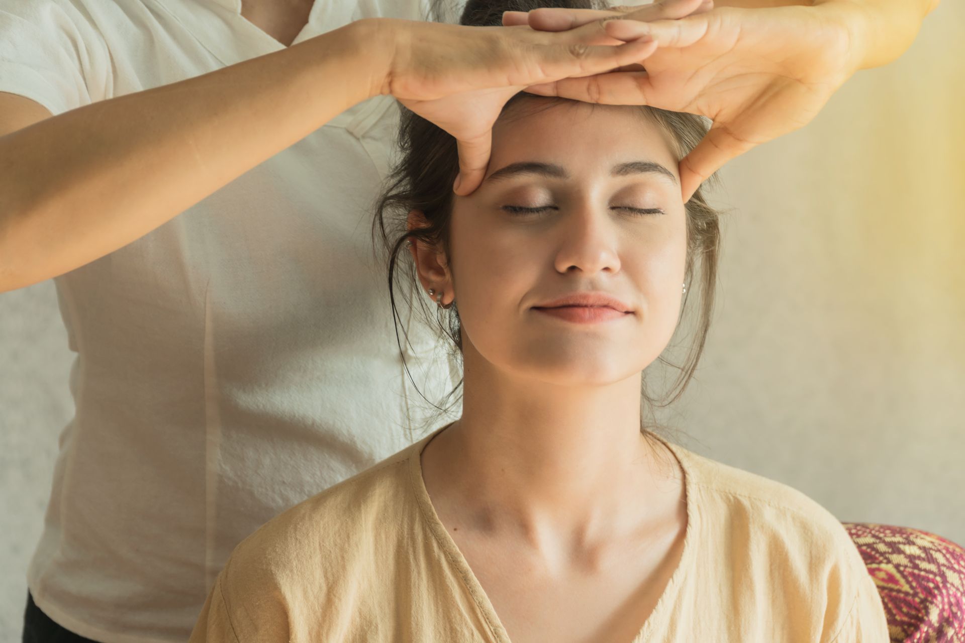 Une femme reçoit un massage de la tête par un massothérapeute.