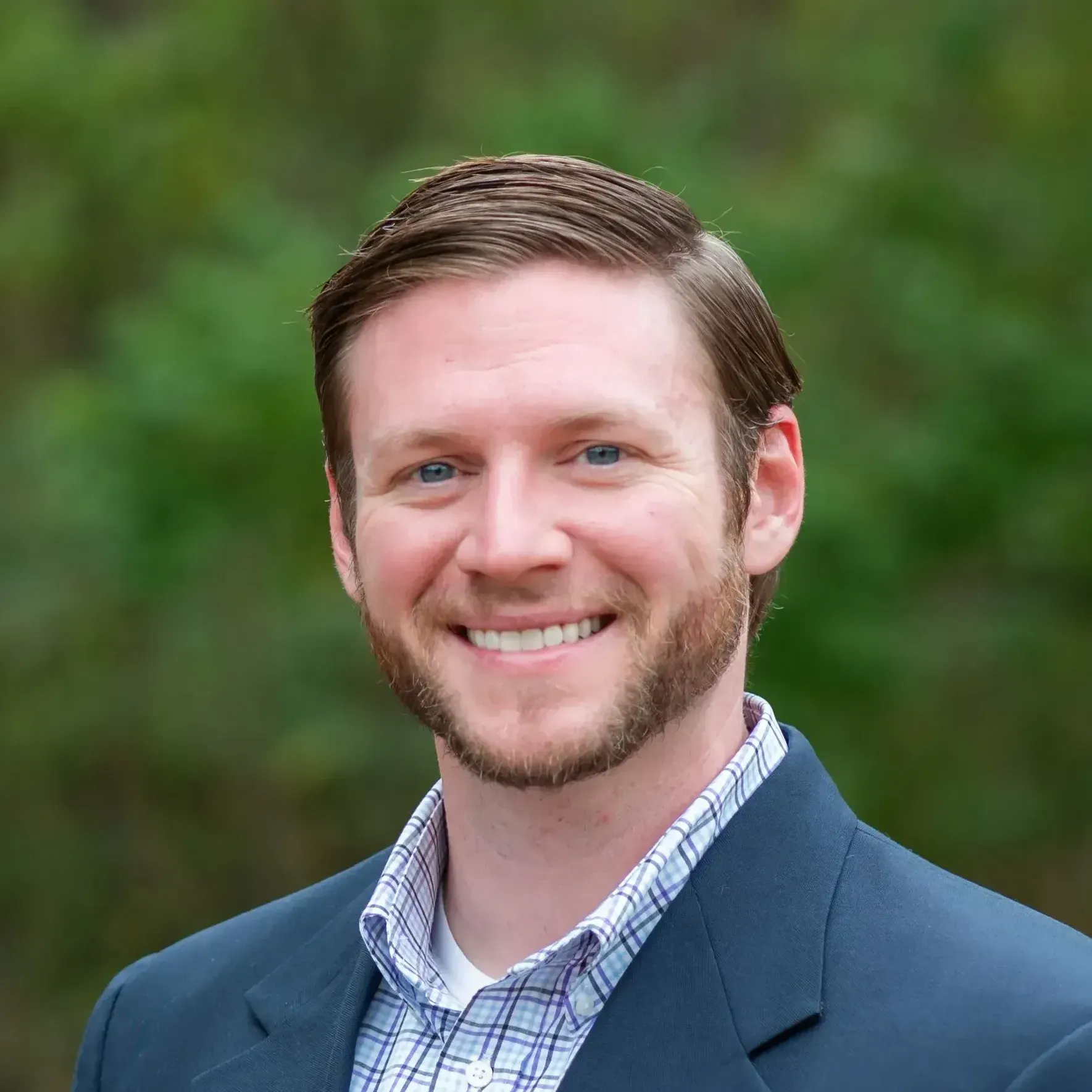 A man with a beard and a blue jacket is smiling for the camera.