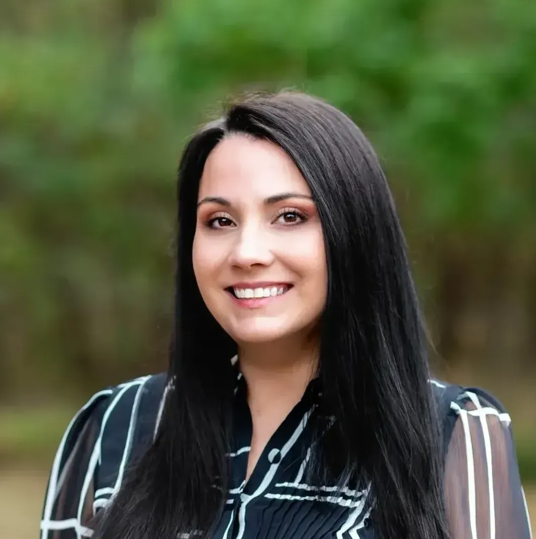 A woman with long black hair is smiling for the camera.
