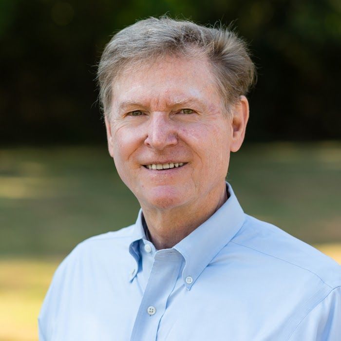 A man in a blue shirt is smiling for the camera.
