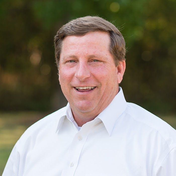 A man in a white shirt is smiling for the camera.