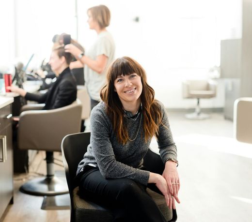 A woman is sitting in a chair in a hair salon.