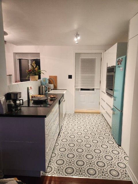 Une cuisine avec des armoires blanches et un réfrigérateur bleu