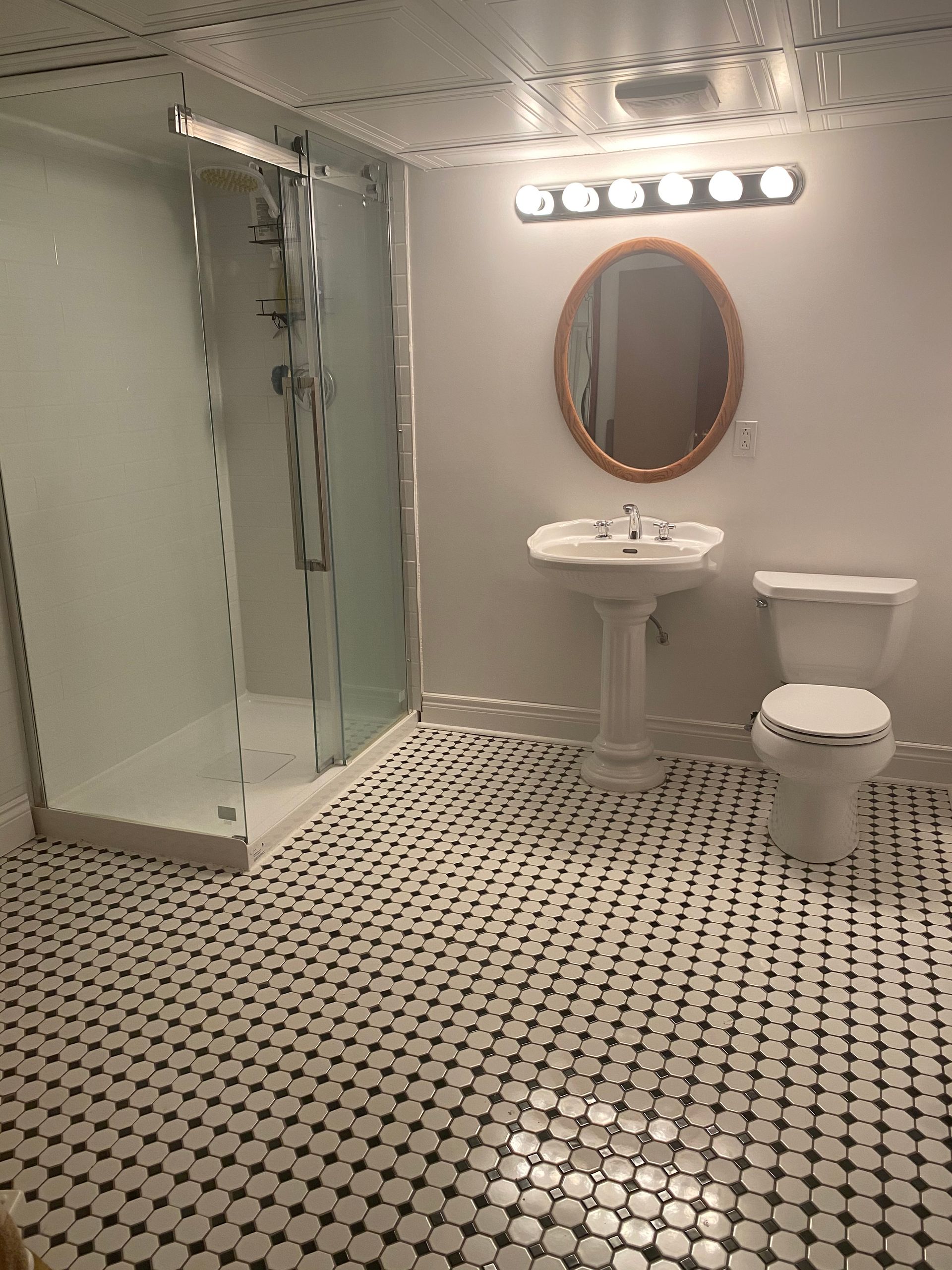 Une salle de bain avec WC , lavabo , douche et miroir.