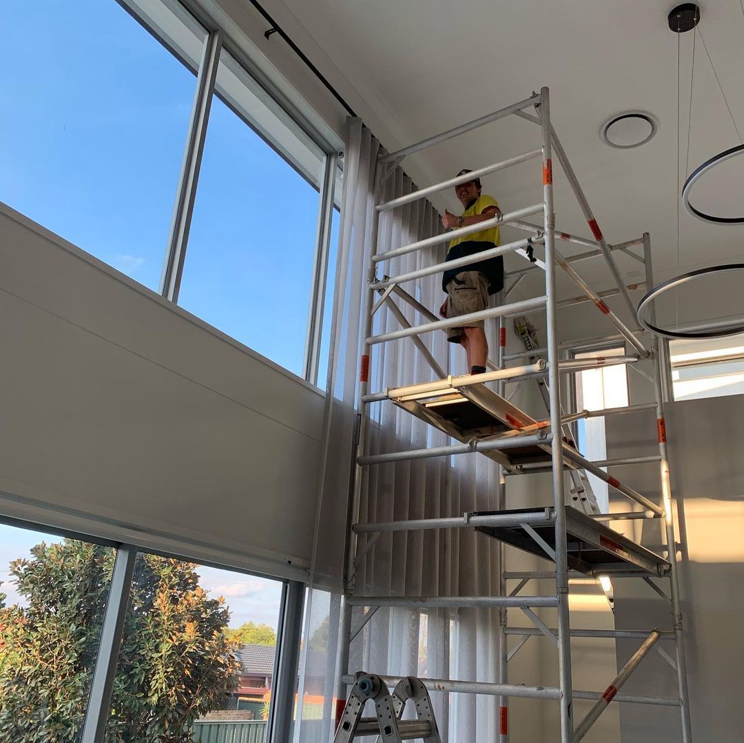 Man On A Scaffolding Installing A Curtains — Studio Curtains & Blinds in Mount Gravatt, QLD