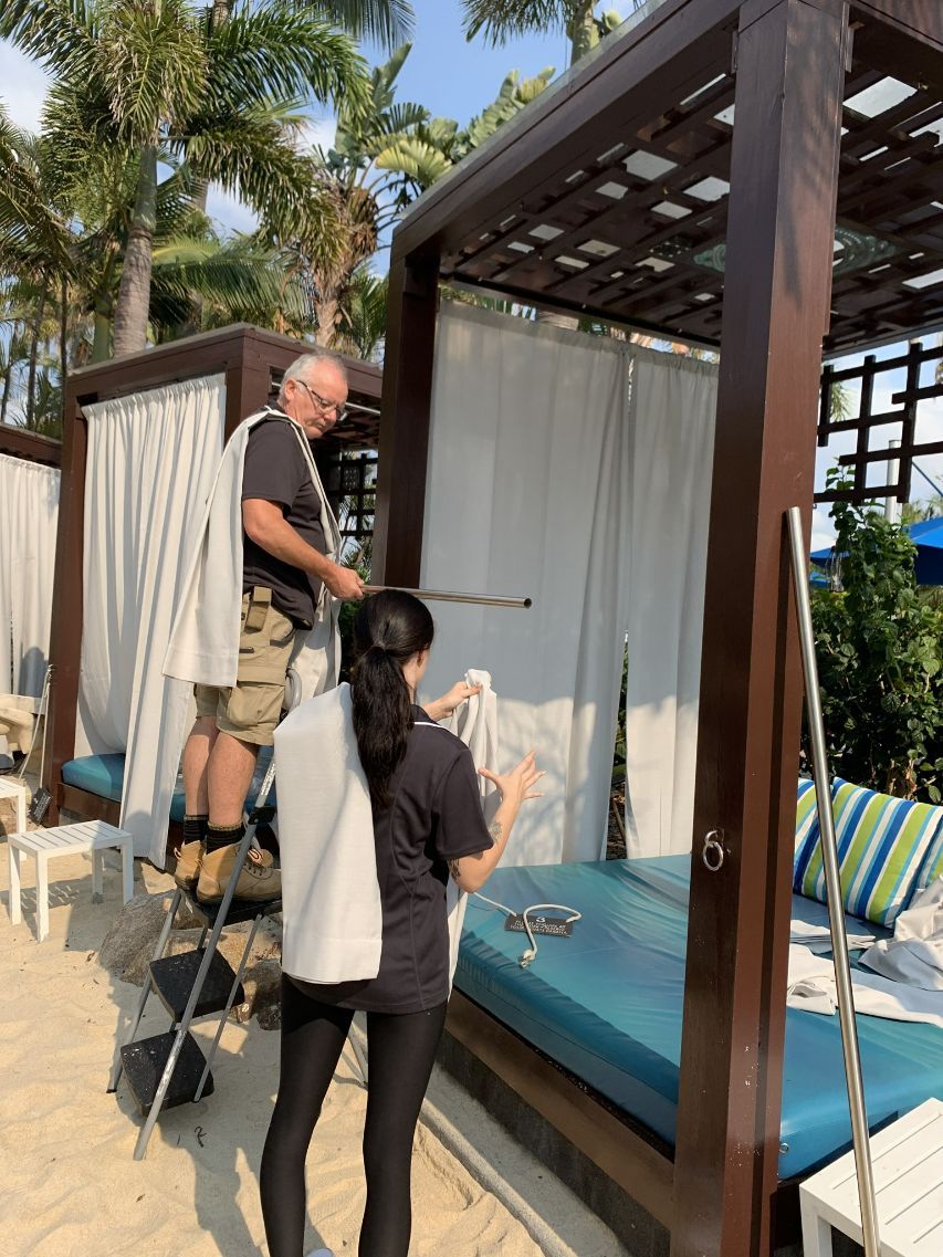 Man & Woman Installing New Drapes On Cabanas — Studio Curtains & Blinds in Mount Gravatt, QLD