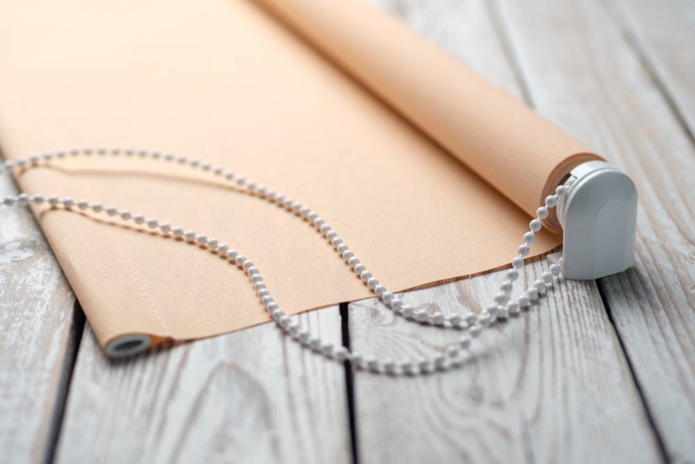 Beige Blockout Blinds On Wooden Table — Studio Curtains & Blinds in Mount Gravatt, QLD