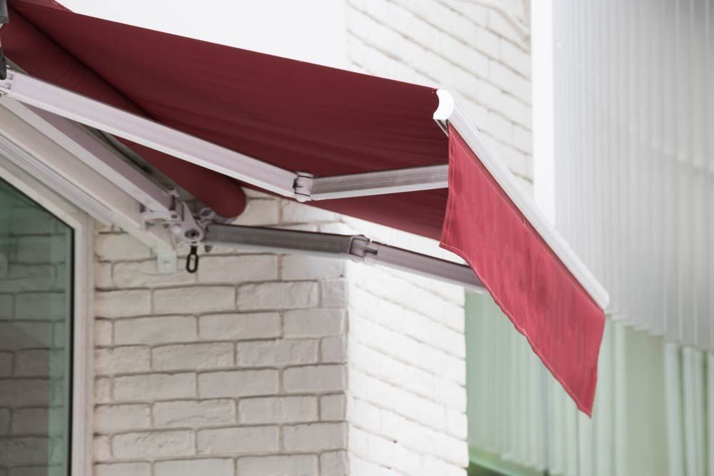 Red Folding Arm Awning Over A Window — Studio Curtains & Blinds in Mount Gravatt, QLD