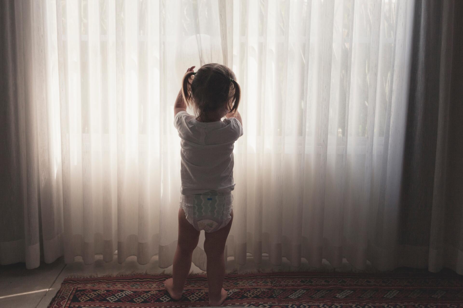 Toddler In Front Of A Window Curtains — Studio Curtains & Blinds in Mount Gravatt, QLD