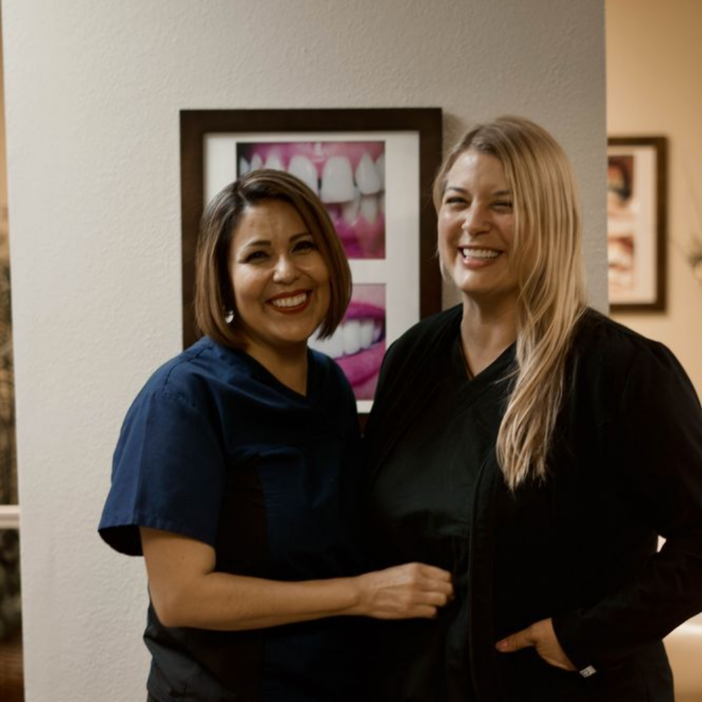 Two smiling women in dental office setting.