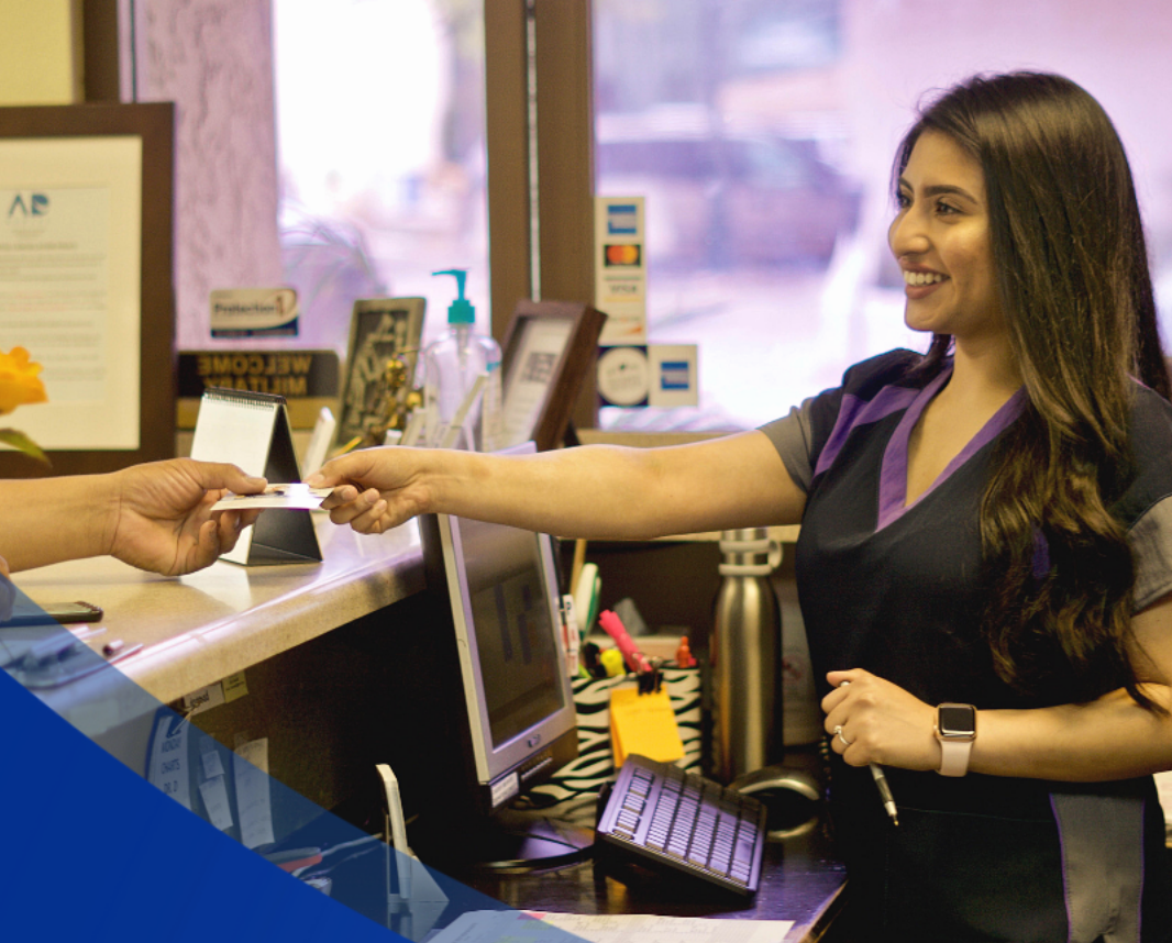Woman at dental office counter taking a card, smiling. Woman at dental office counter taking a card, smiling.