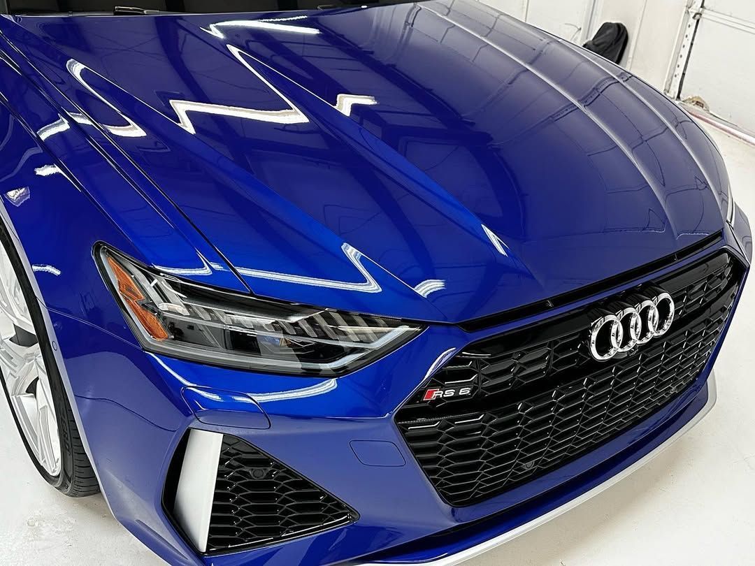 A blue audi rs7 is parked on a white surface.