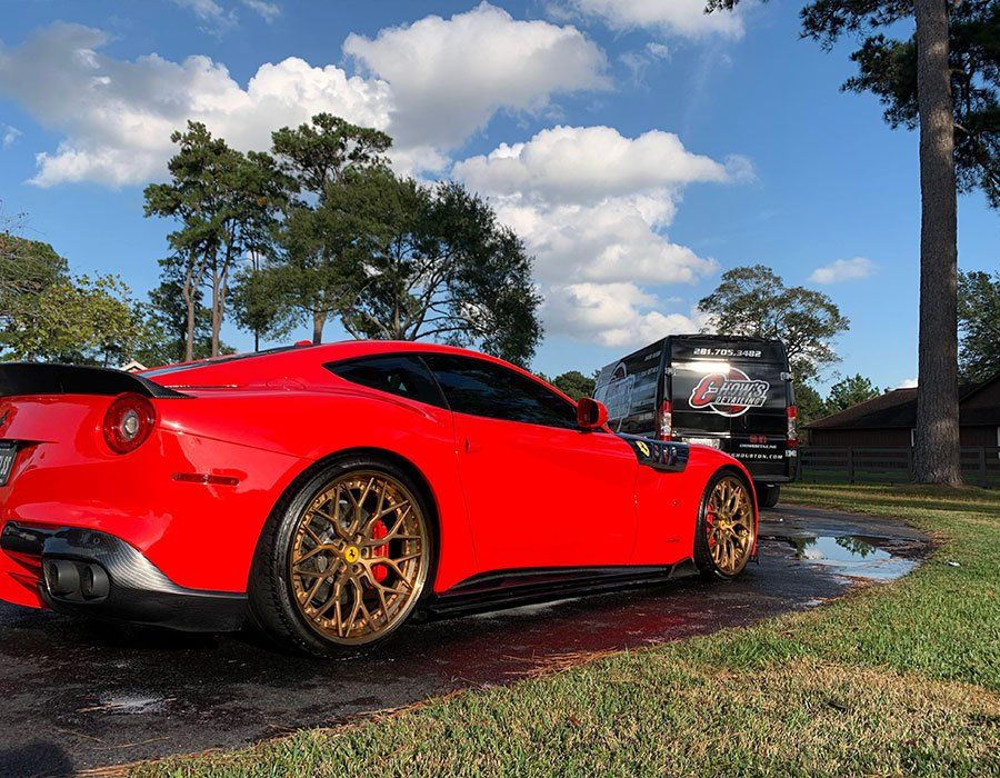 a red ferrari is parked in a driveway next to a trailer .