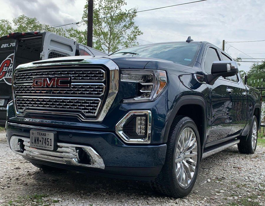 a blue gmc truck is parked on a gravel road .