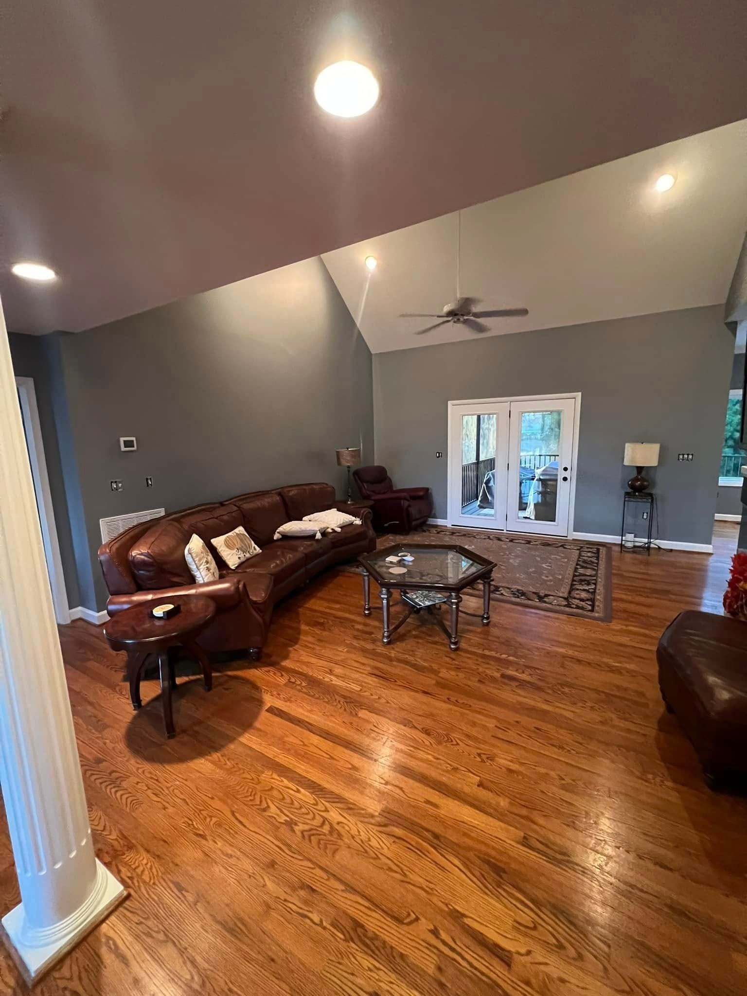 Living room with wood floors, a brown leather sofa, and glass-topped coffee table.