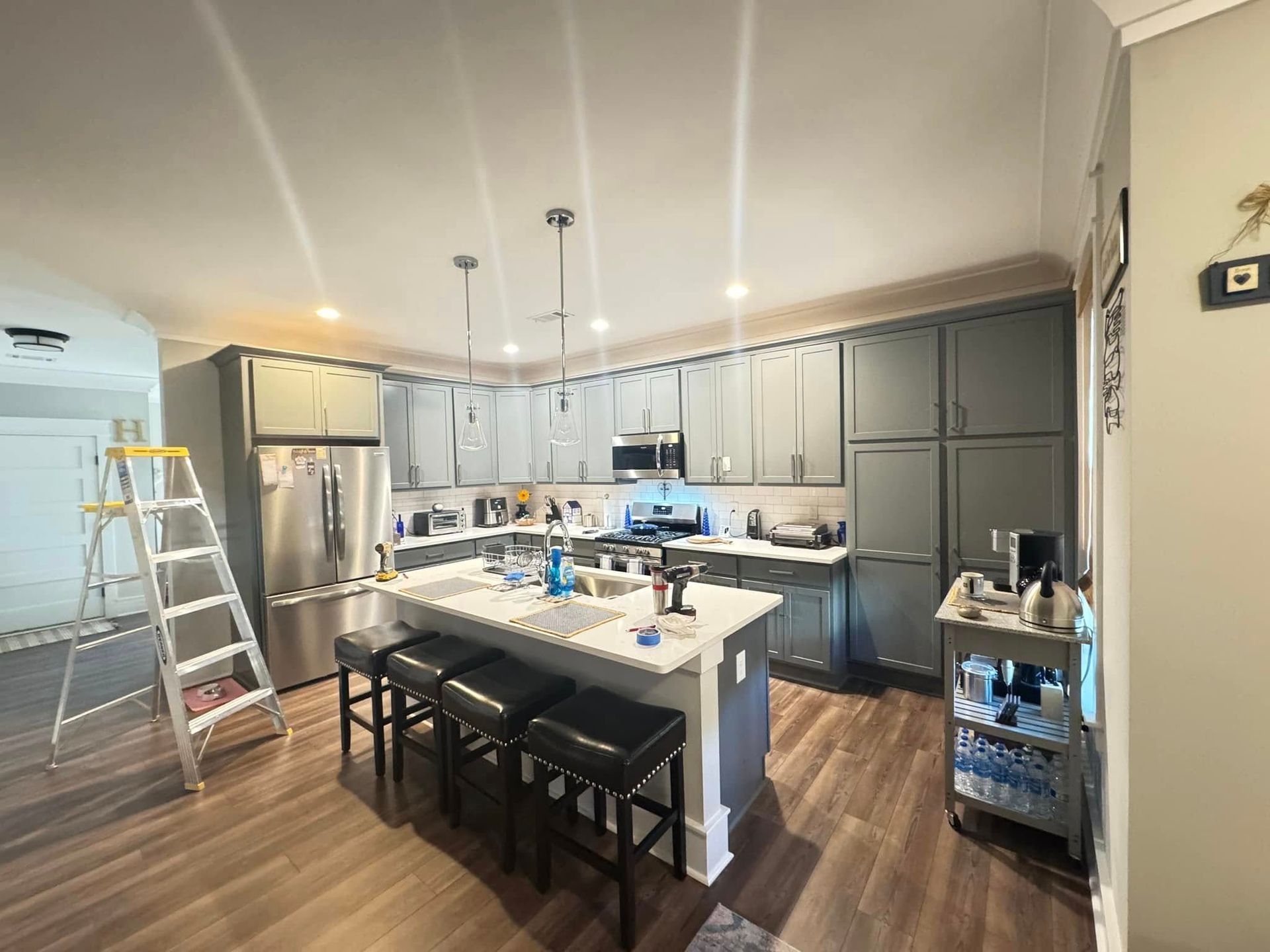 A modern kitchen with gray cabinets, stainless steel appliances, and a white island with bar stools.