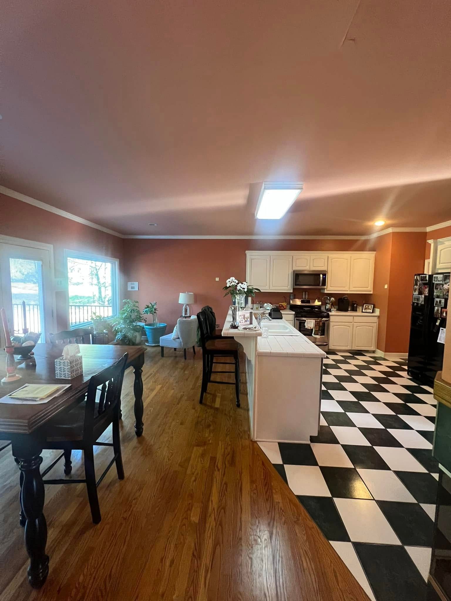 Interior view of a kitchen and dining area with checkered floors, wood floors, and a terracotta-colored ceiling.