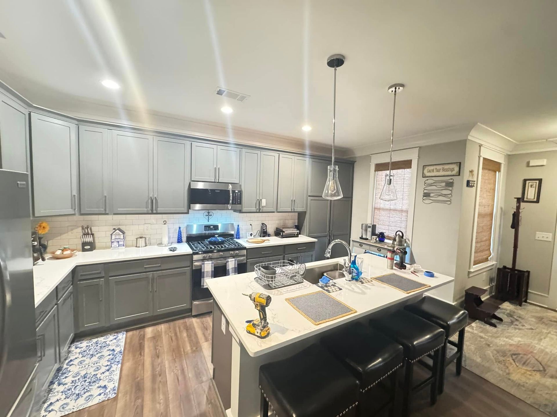 Gray kitchen with white countertops, stainless steel appliances, and a breakfast bar with stools.