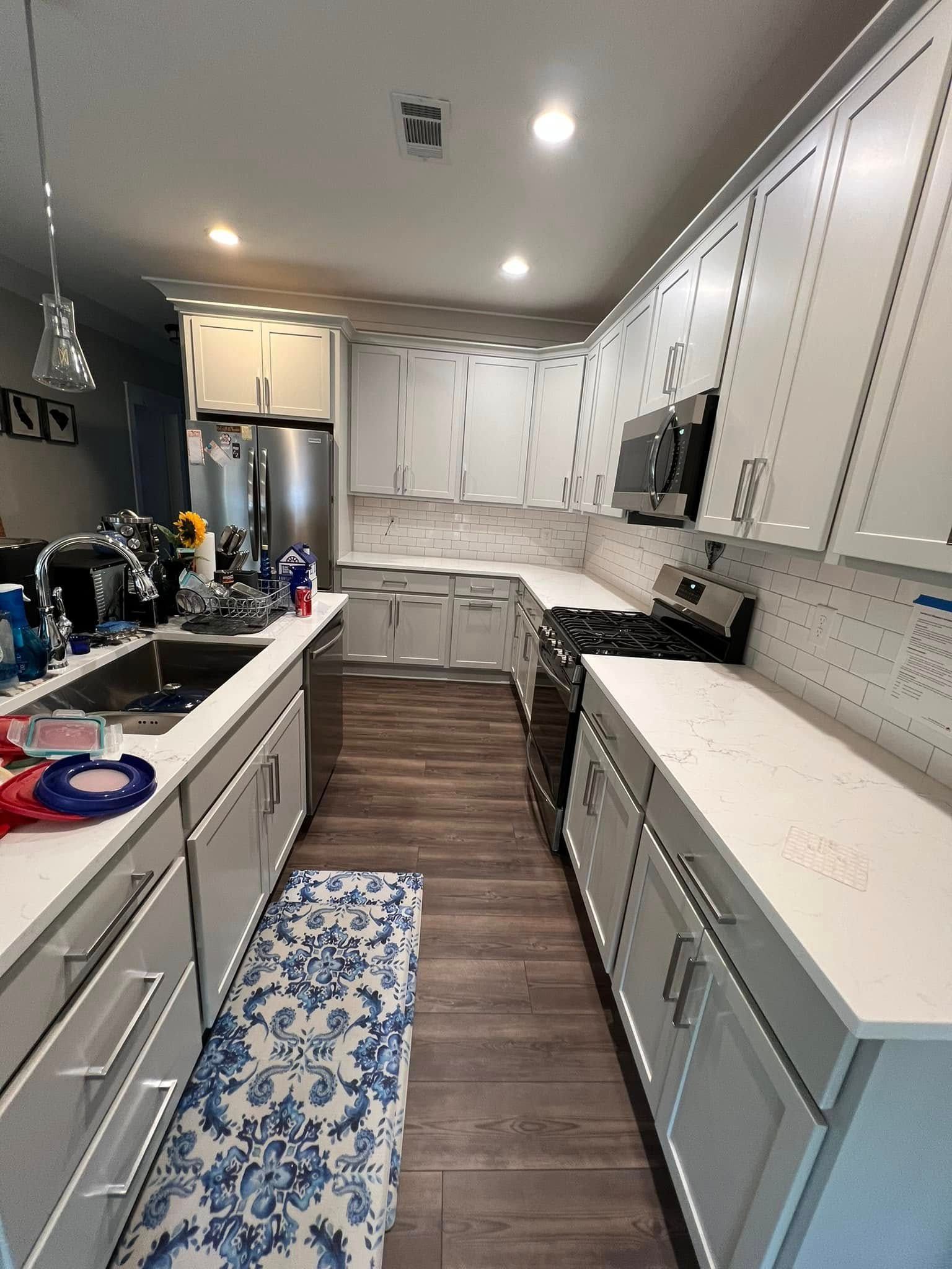 Modern kitchen with white cabinets, stainless steel appliances, and light countertops.
