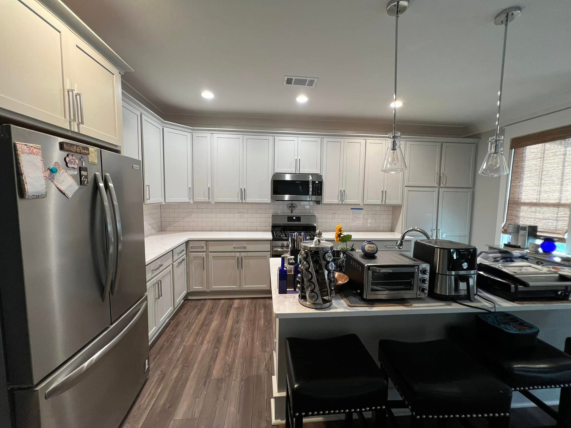 Modern kitchen with stainless steel appliances, light gray cabinets, and an island.