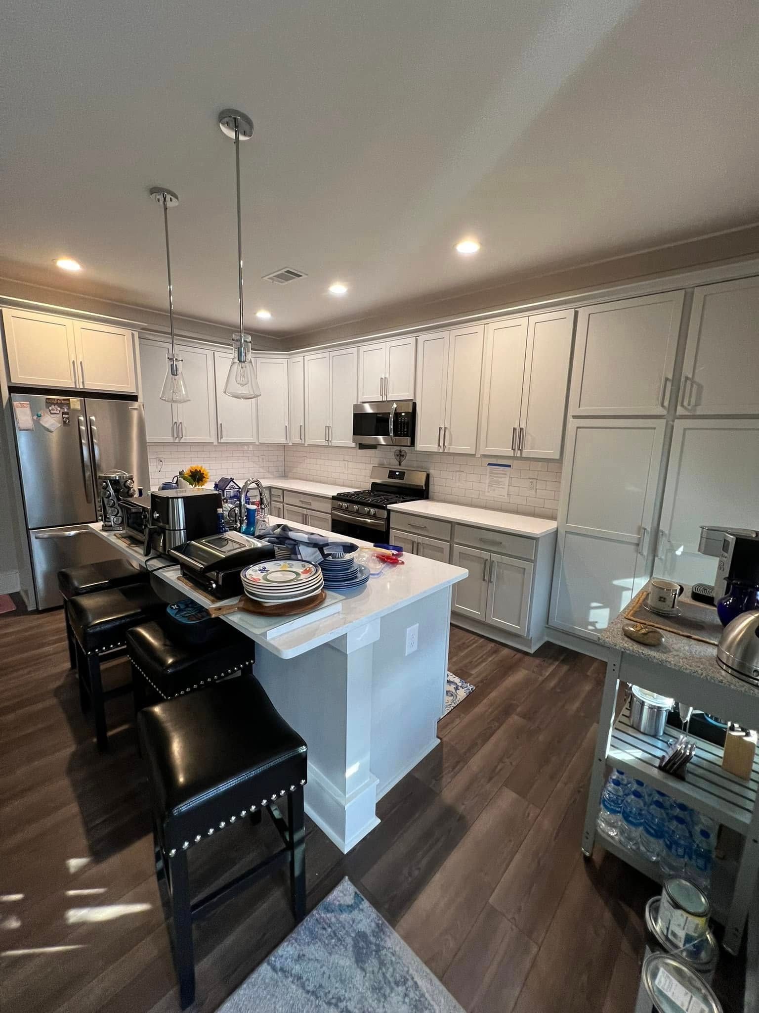 Modern kitchen with island seating, gray cabinets, and stainless steel appliances.