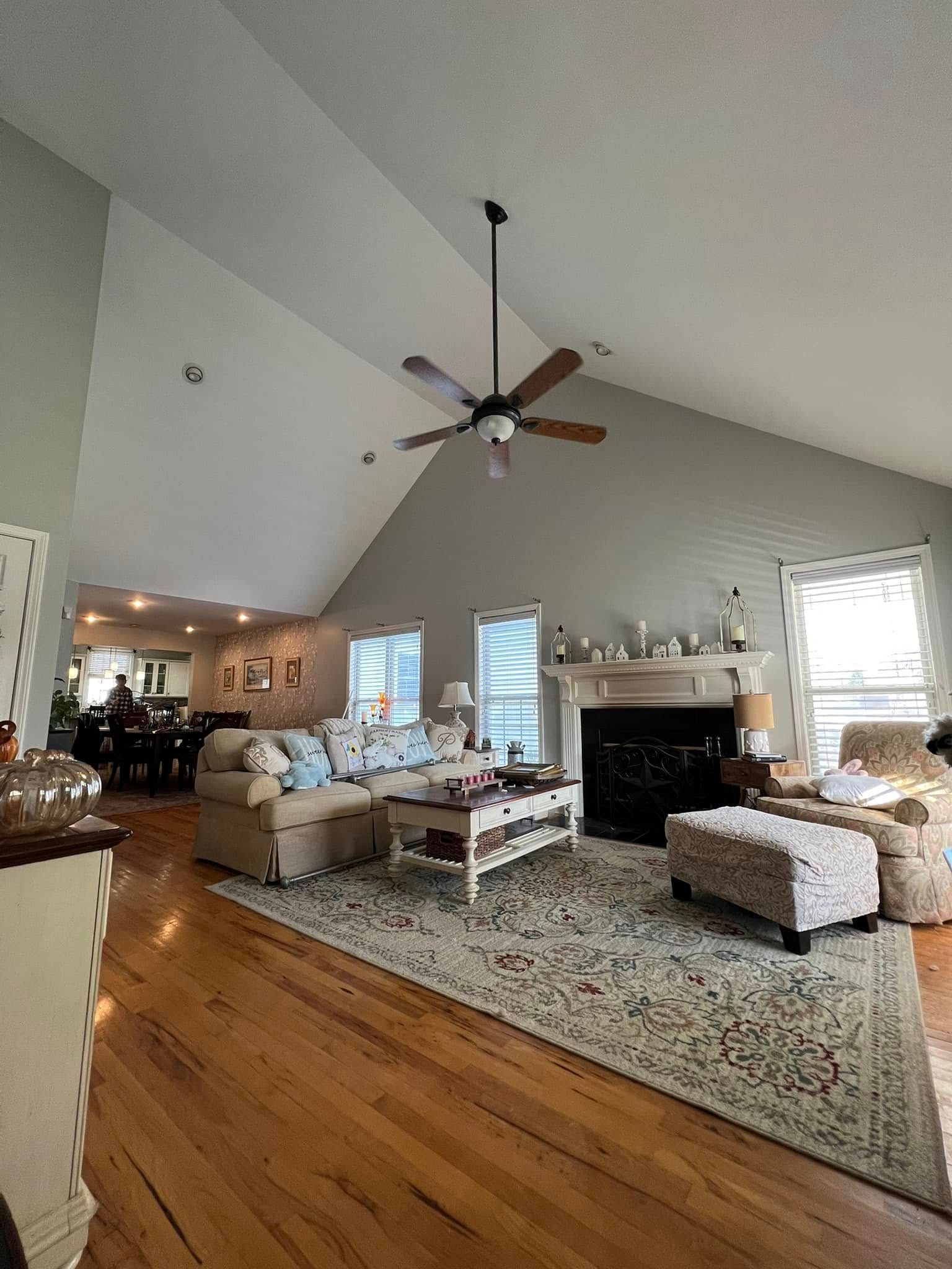 Living room with vaulted ceiling, beige sofa, fireplace, and wood floors.