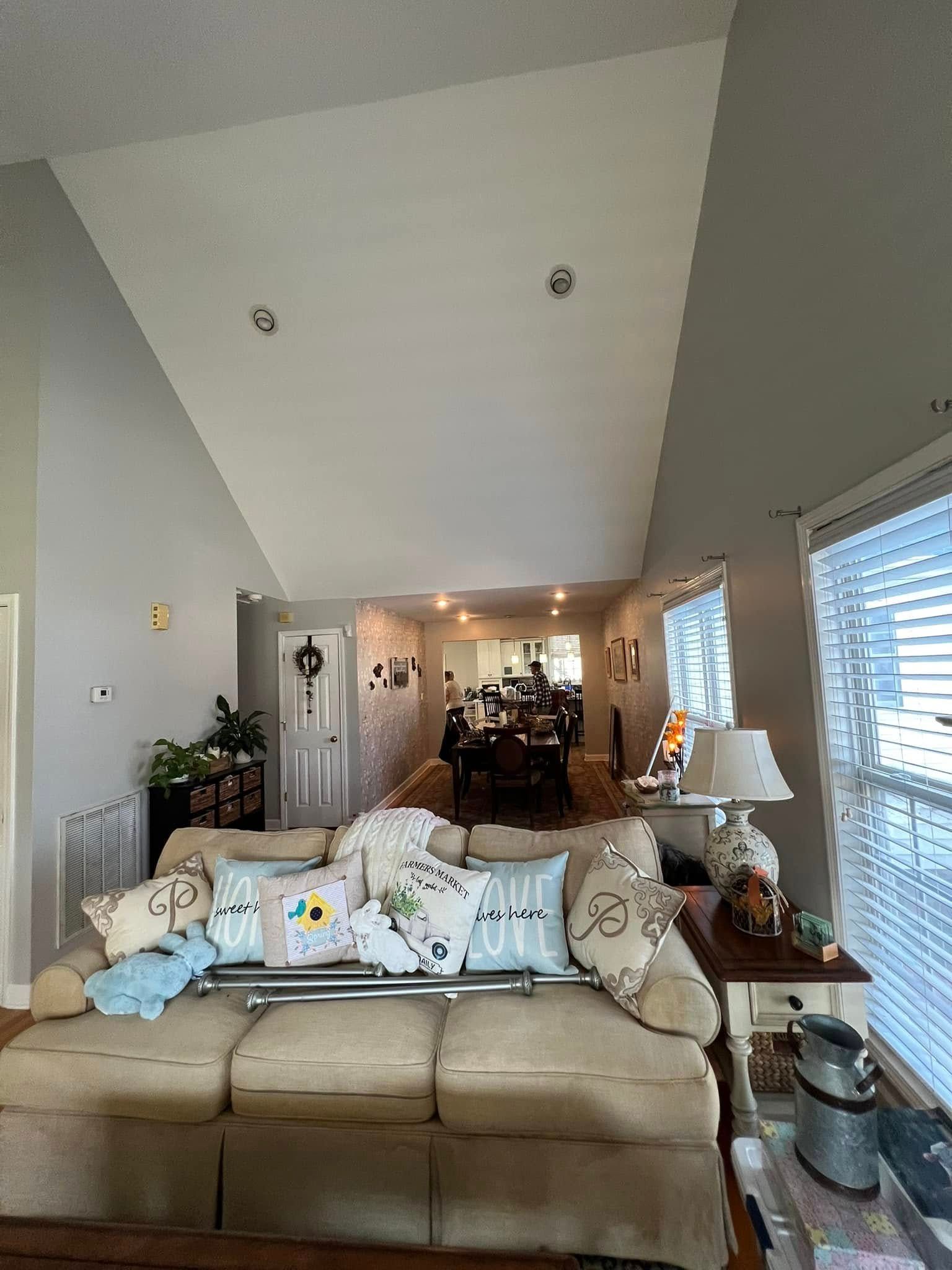 Living room with tan sofa, pillows, and view to dining area; light colors.