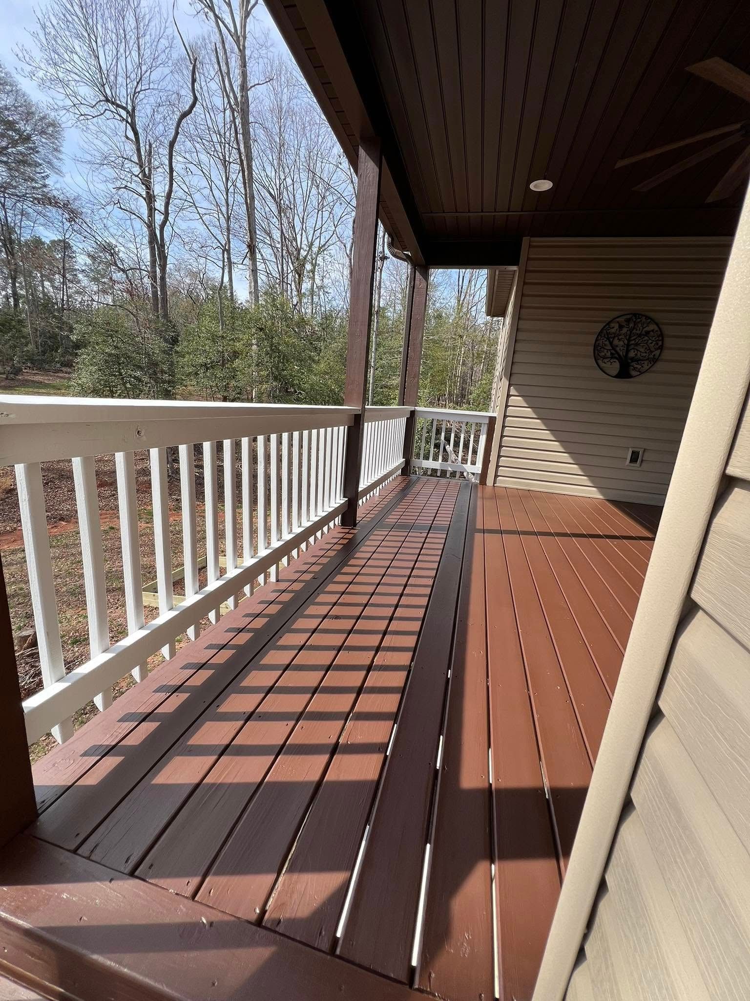 Brown and white porch with white railing, brown deck, and tan siding.