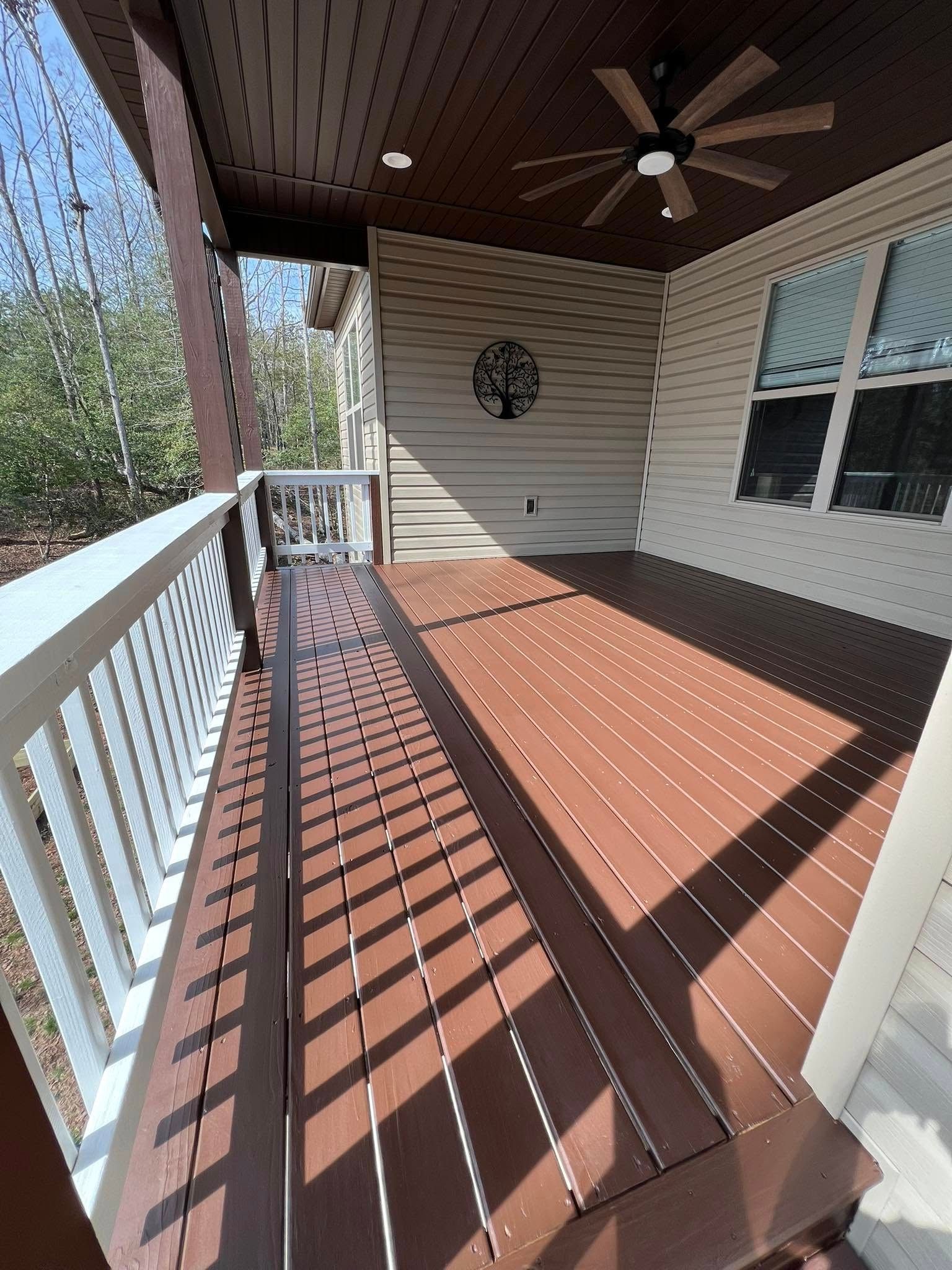 Wooden deck with white railing and brown ceiling; a metal tree decorates the wall.