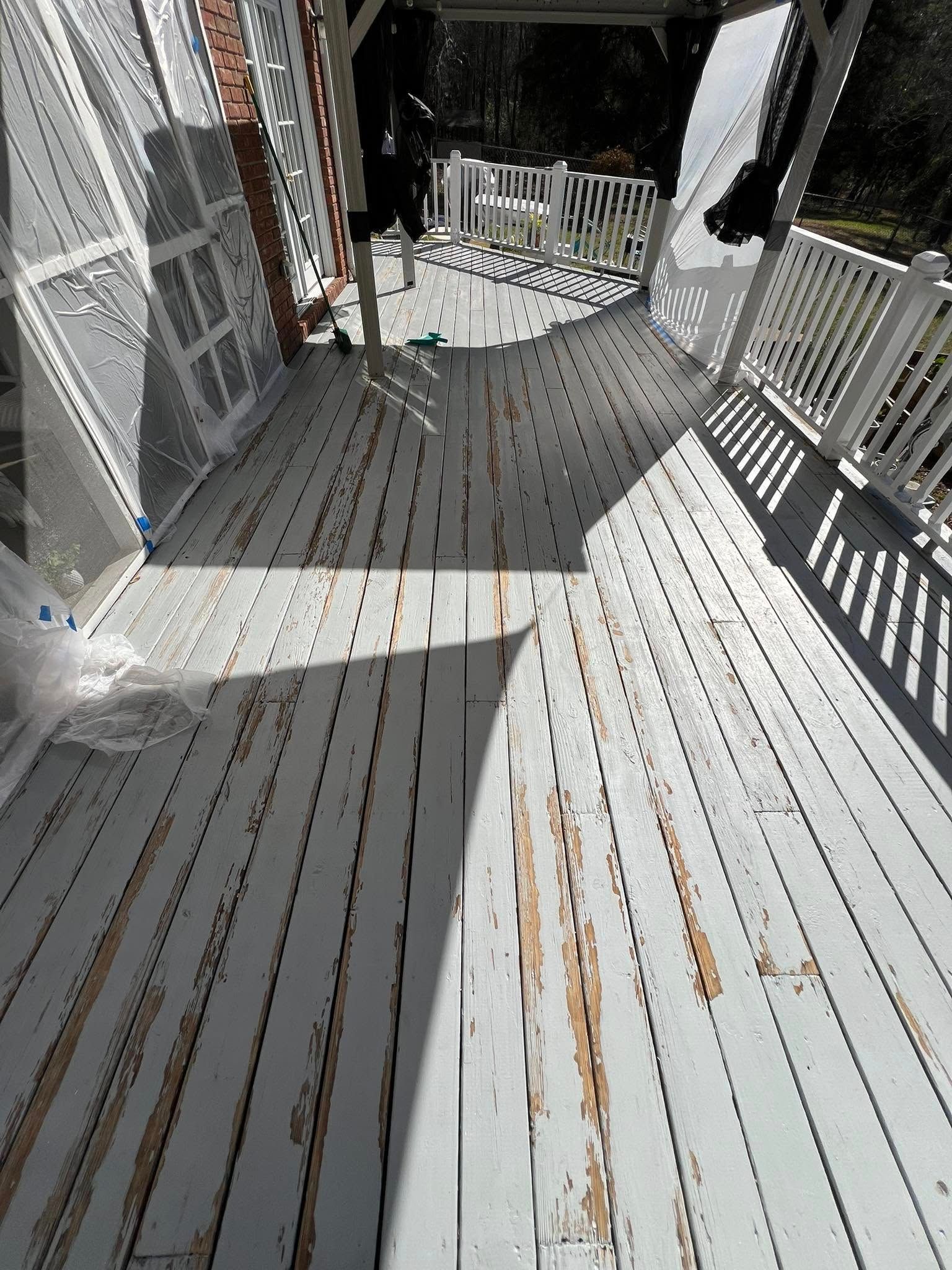 Wooden deck with peeling white paint, exposed wood, and white railing.