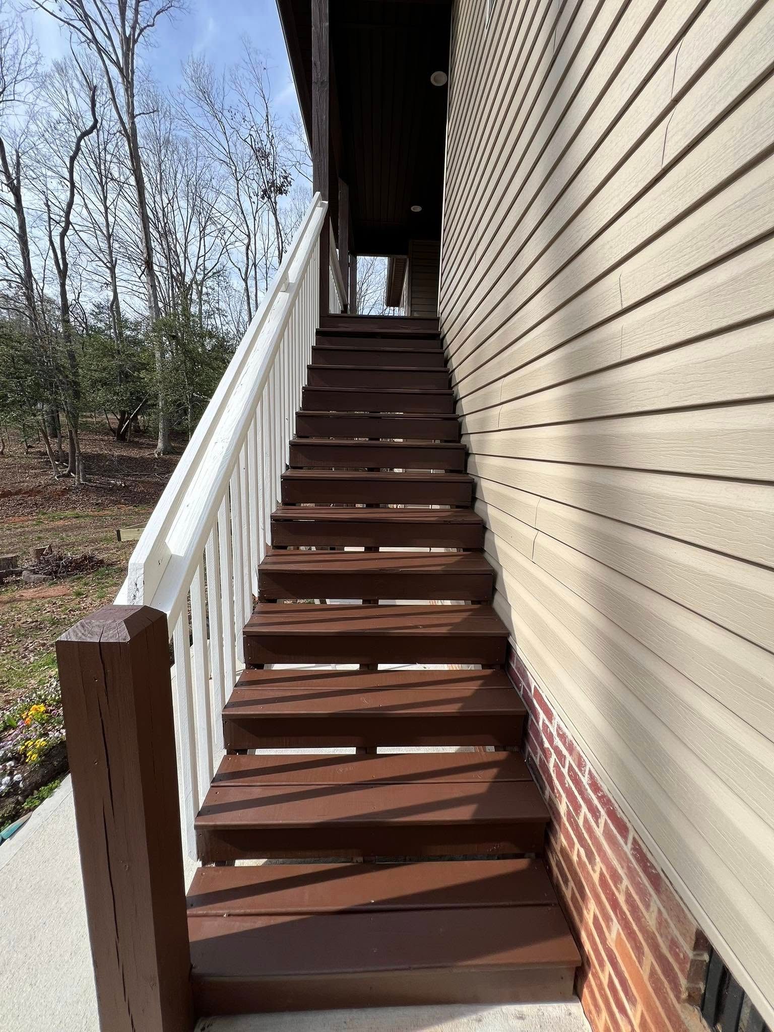Outdoor staircase leading up to a building entrance. Brown steps, white railing, beige siding.