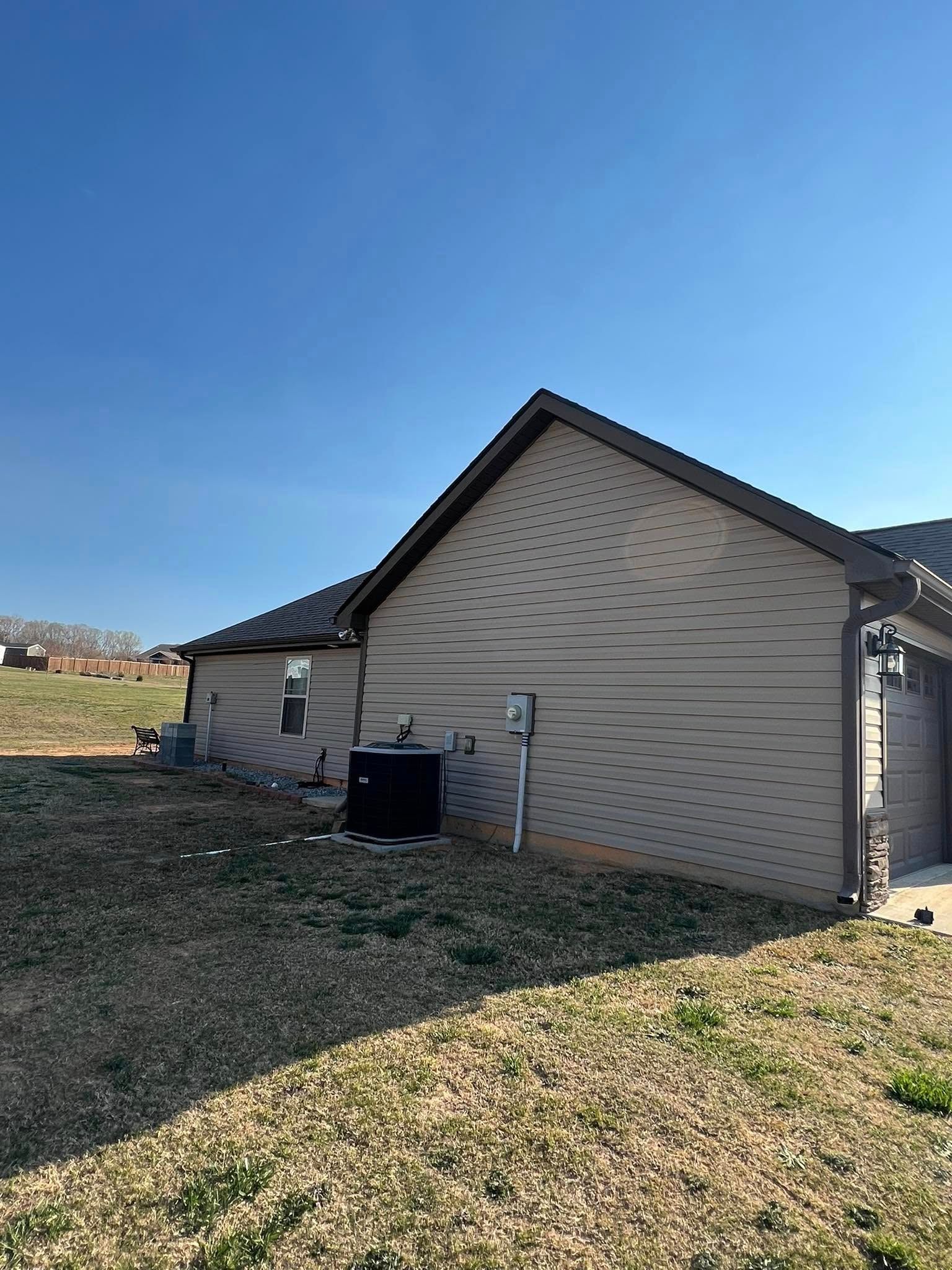 Tan house exterior with brown roof and blue sky.