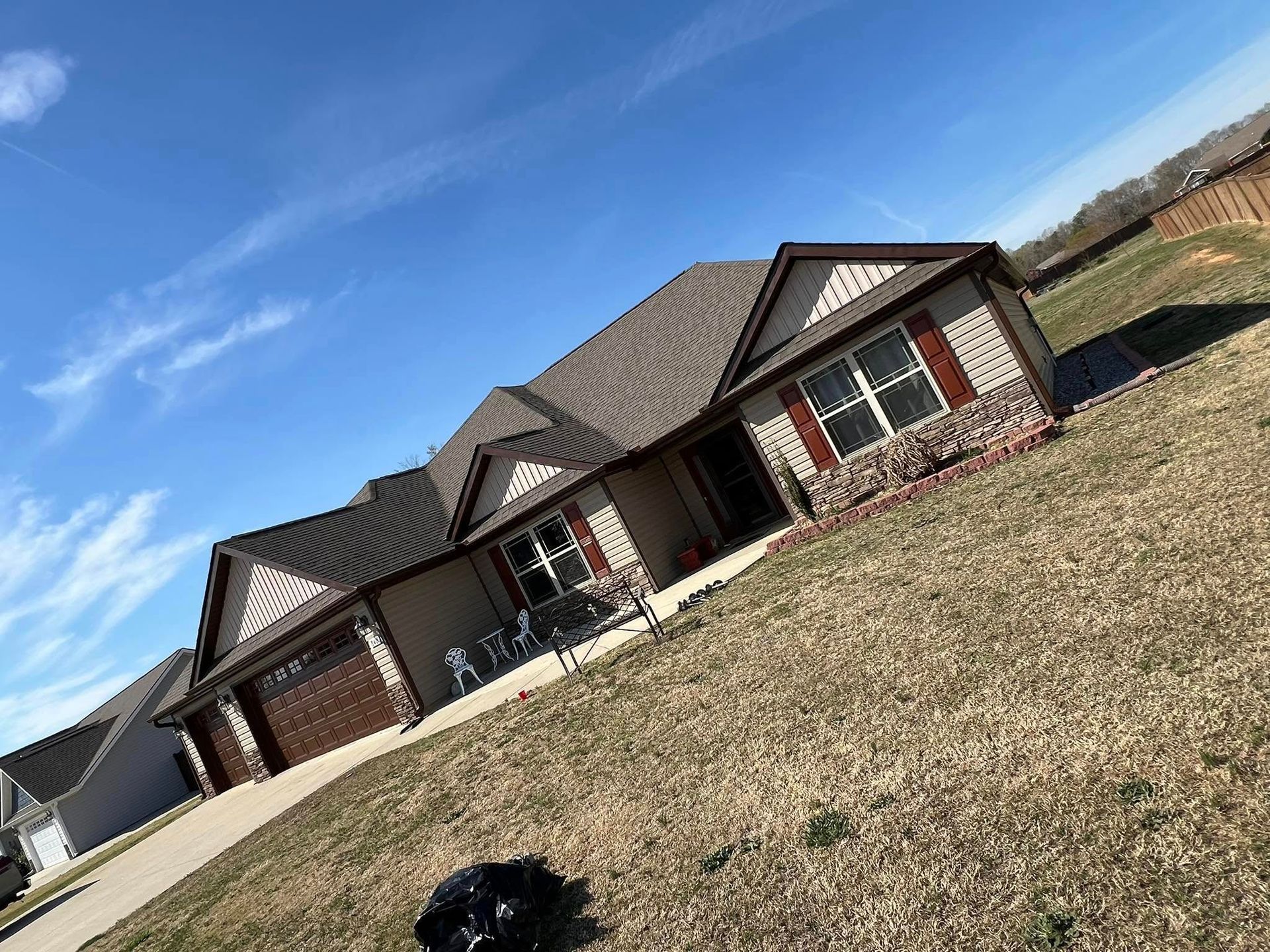 Tan house with brown roof and accents on a sunny day.