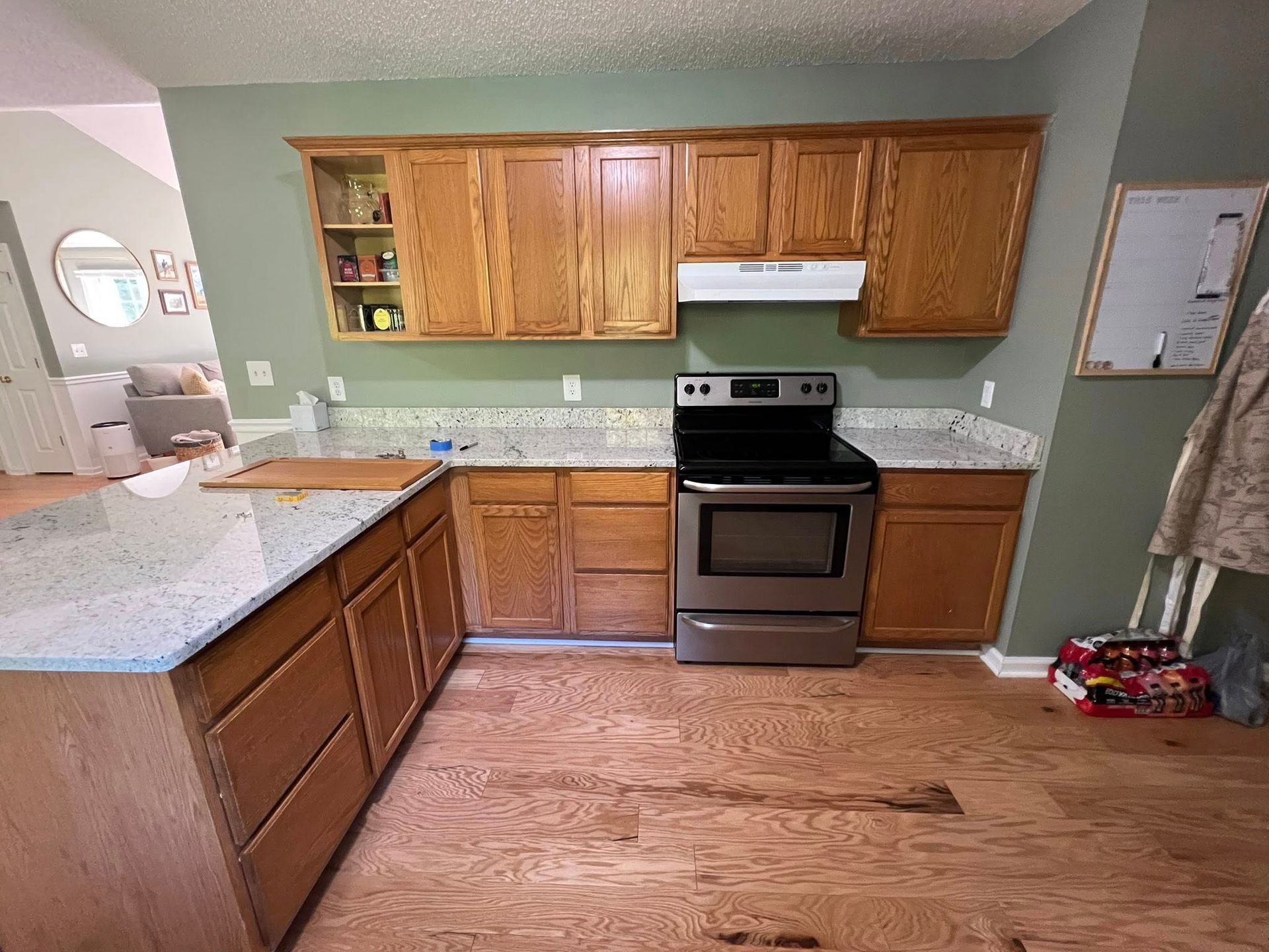 Kitchen with wood cabinets, granite countertops, stainless steel oven, and hardwood floor.