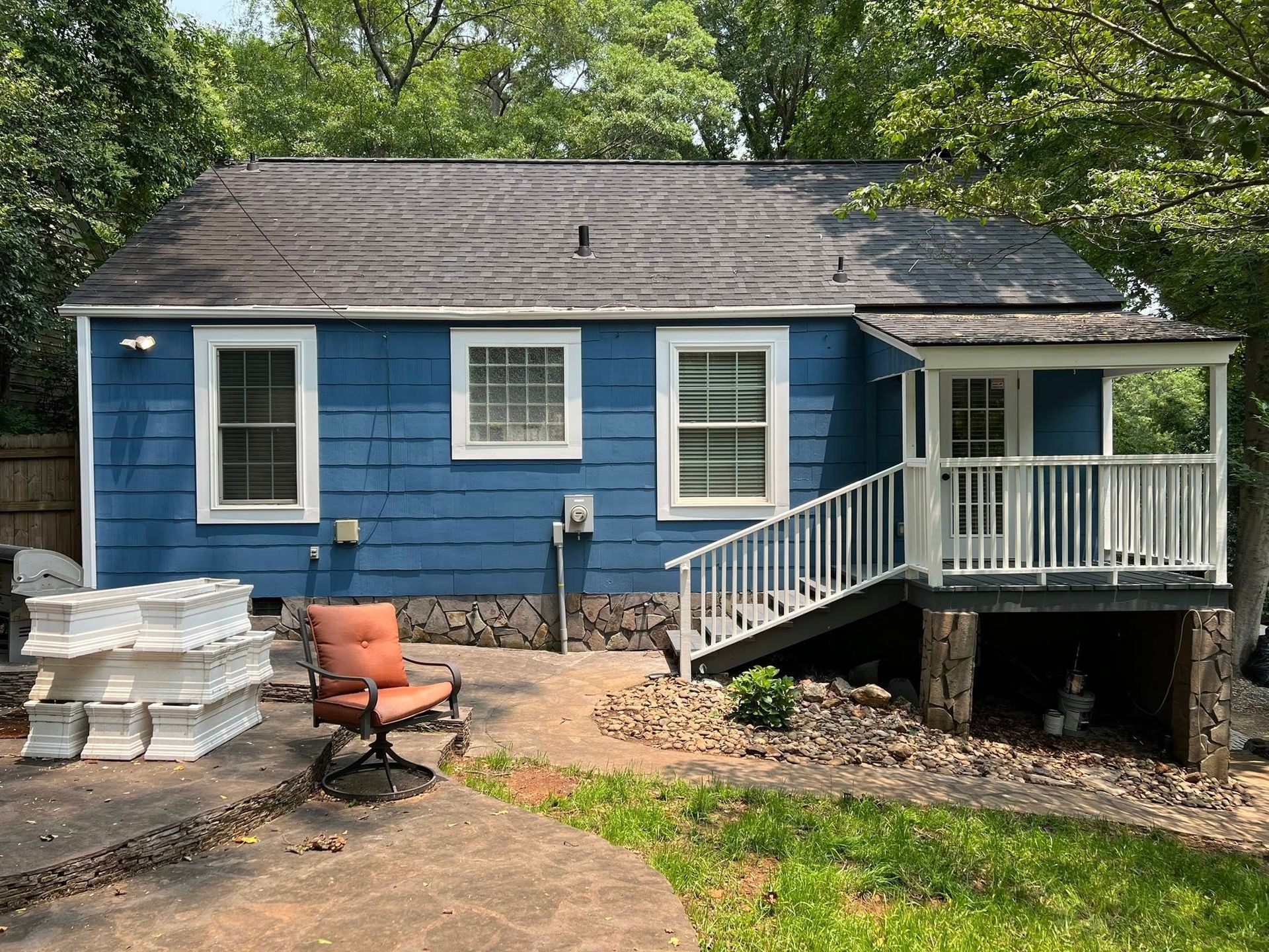 Blue house with white trim, small porch, and outdoor seating.