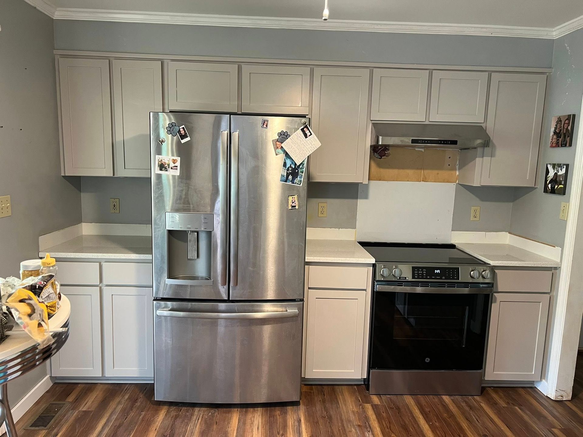 Kitchen with gray cabinets, white counters, stainless steel appliances, and a wooden floor.