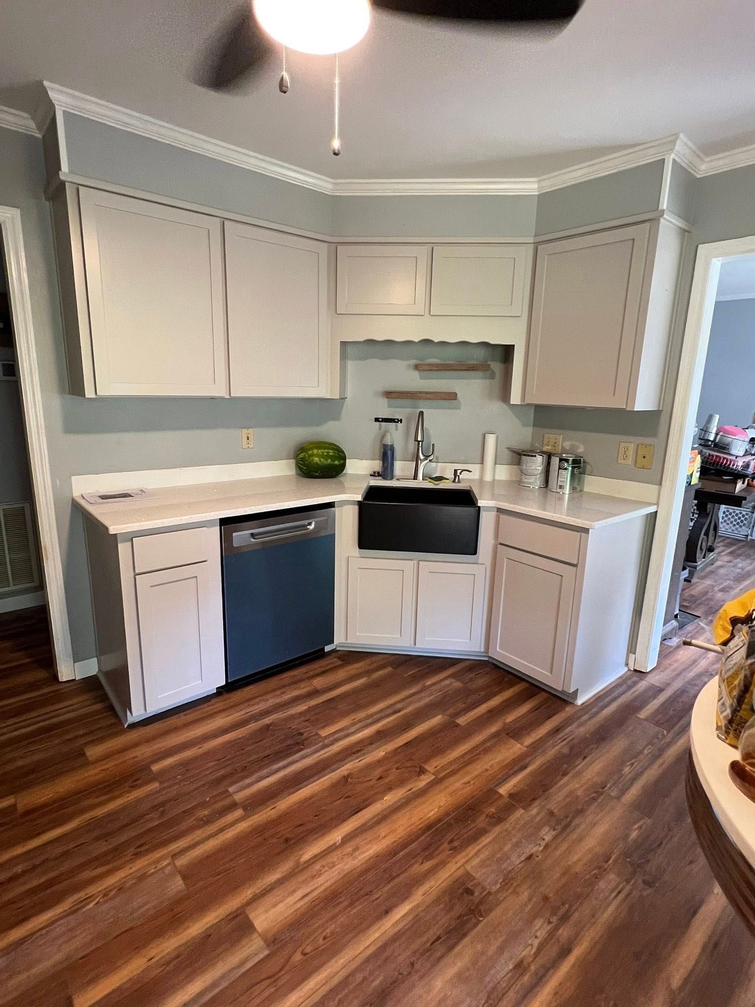 Kitchen with light cabinets, dark sink, dishwasher, and wooden floor.