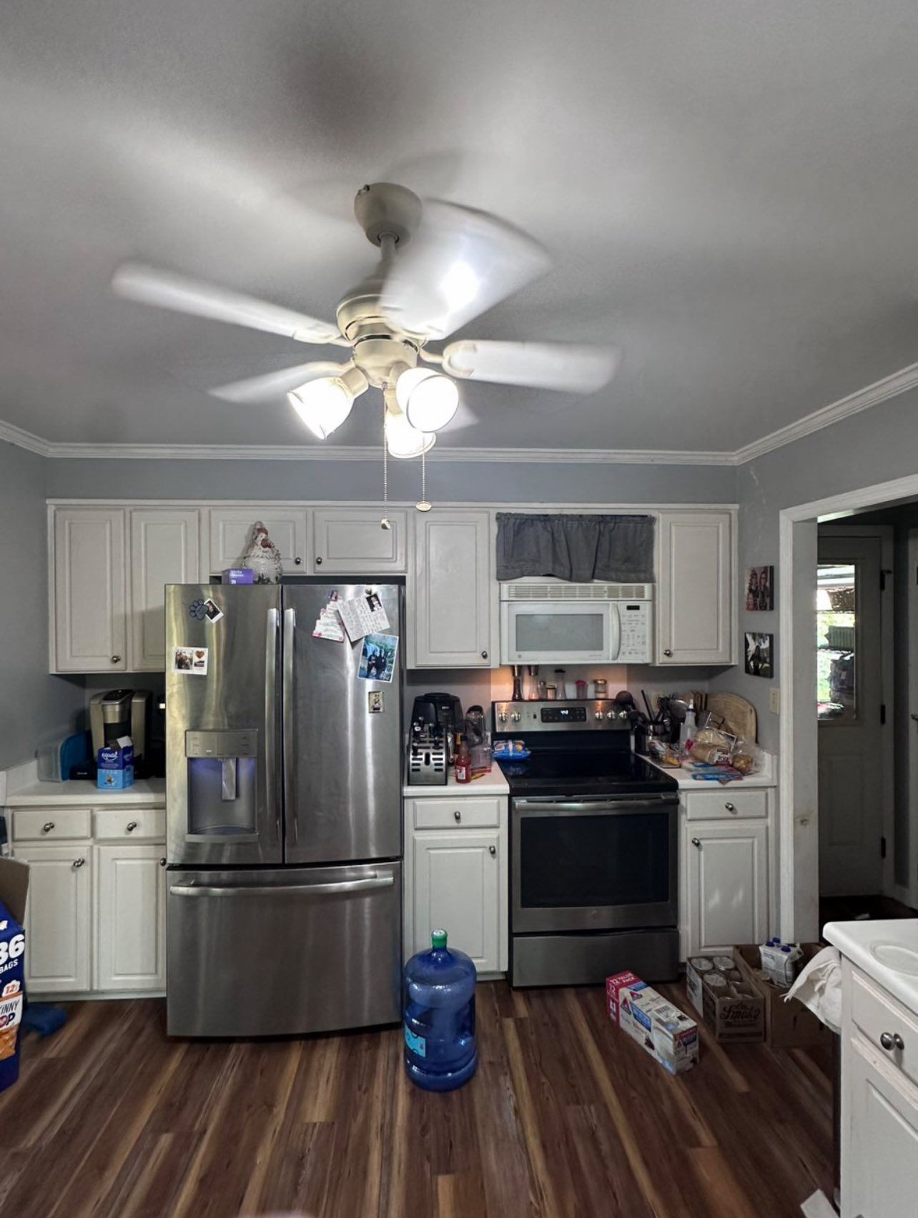 Kitchen with white cabinets, stainless steel appliances, and a ceiling fan.