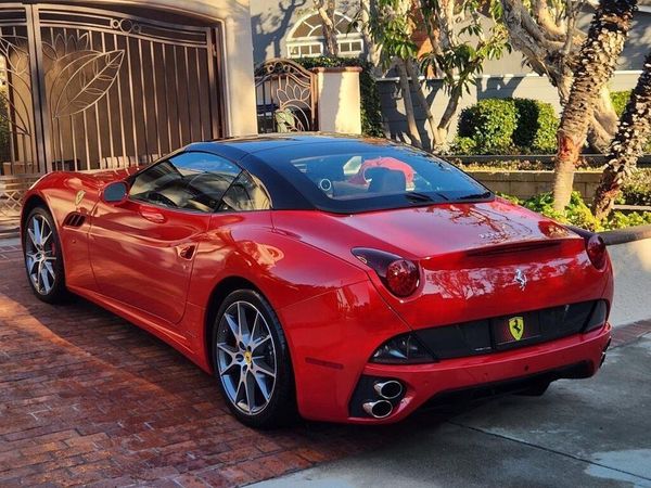 A red ferrari is parked in front of a house