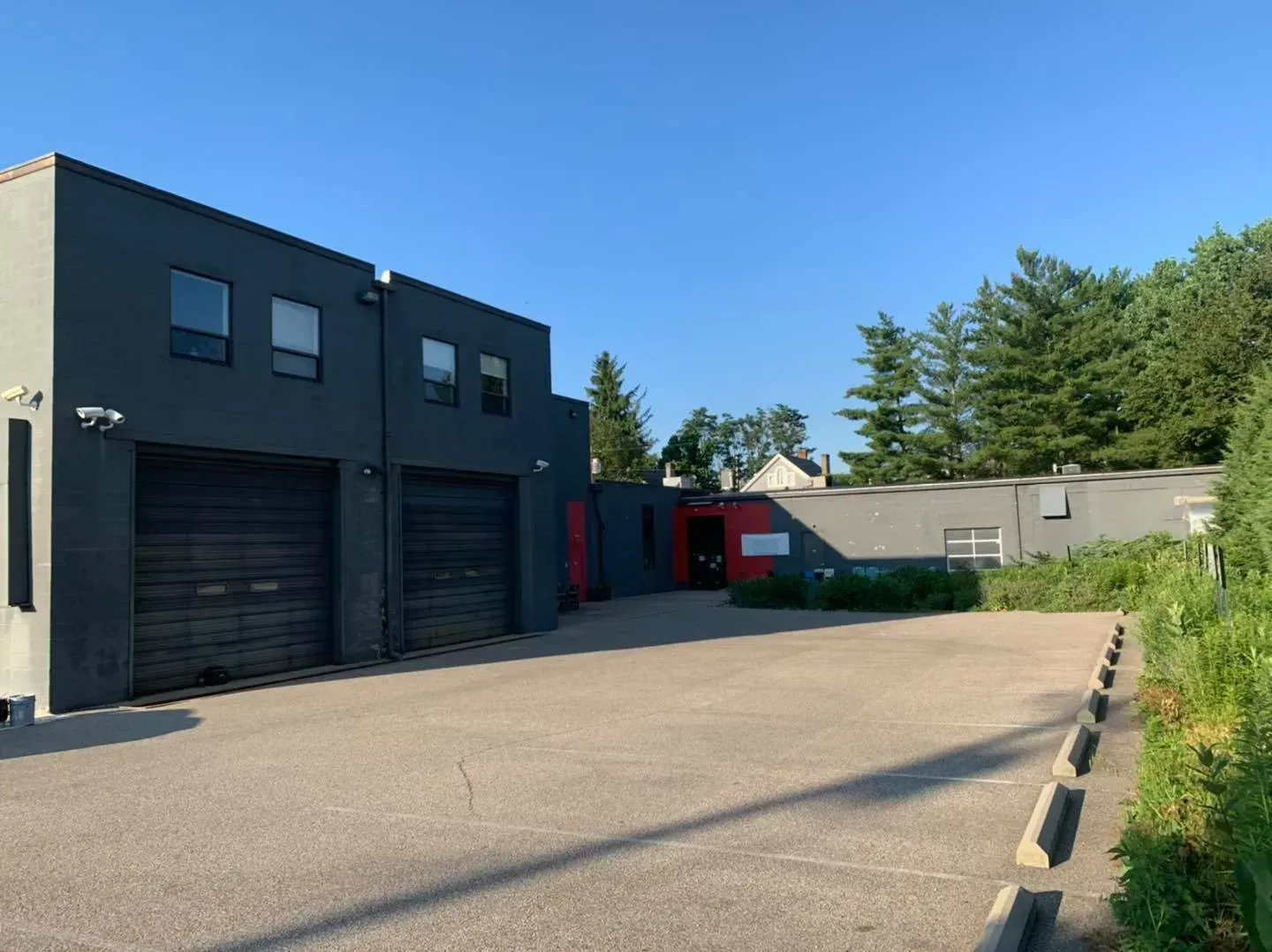 A large building with a lot of garage doors and a parking lot in front of it.